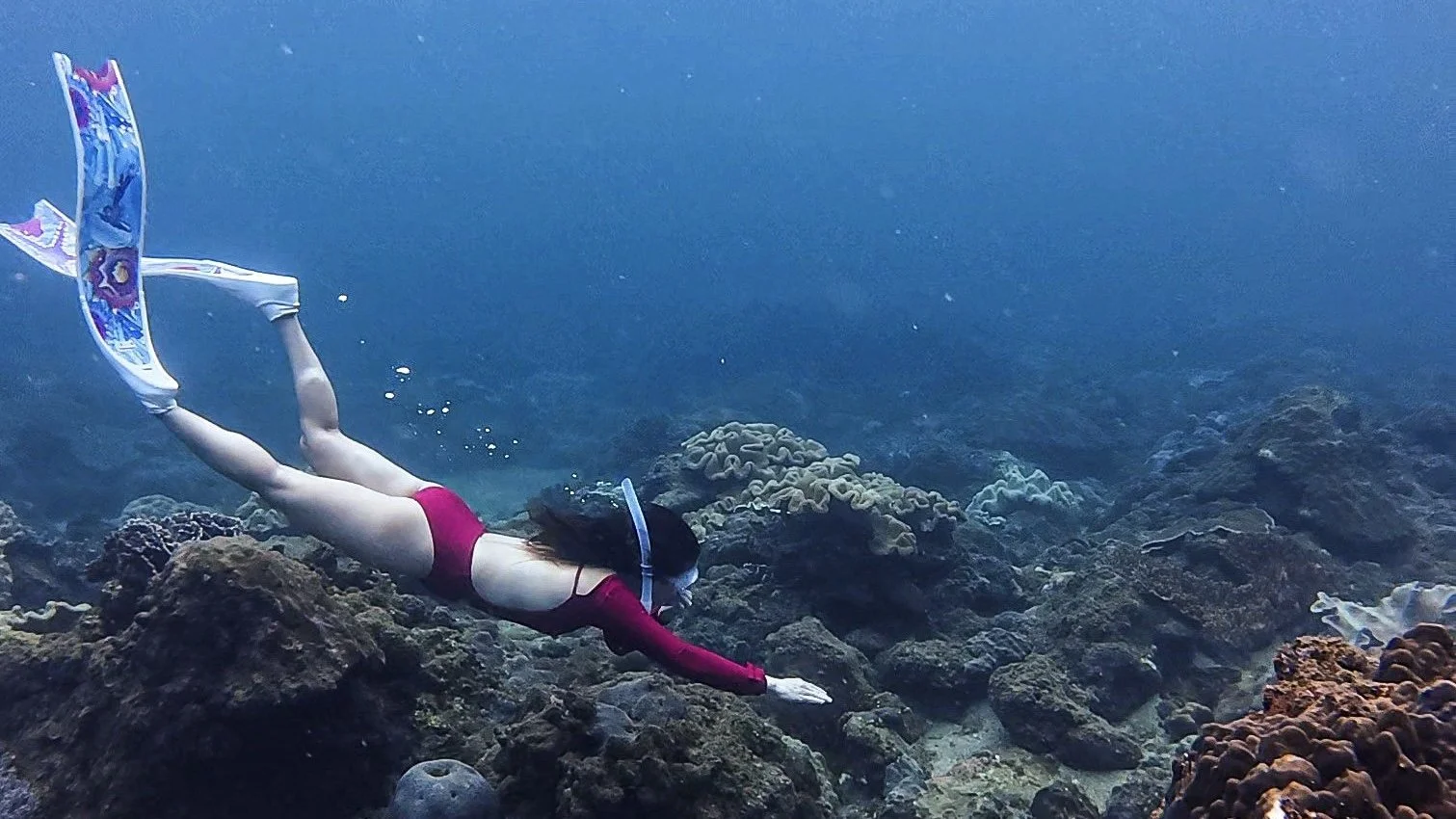 Traveller snorkelling above coral near Pink Beach in Lombok