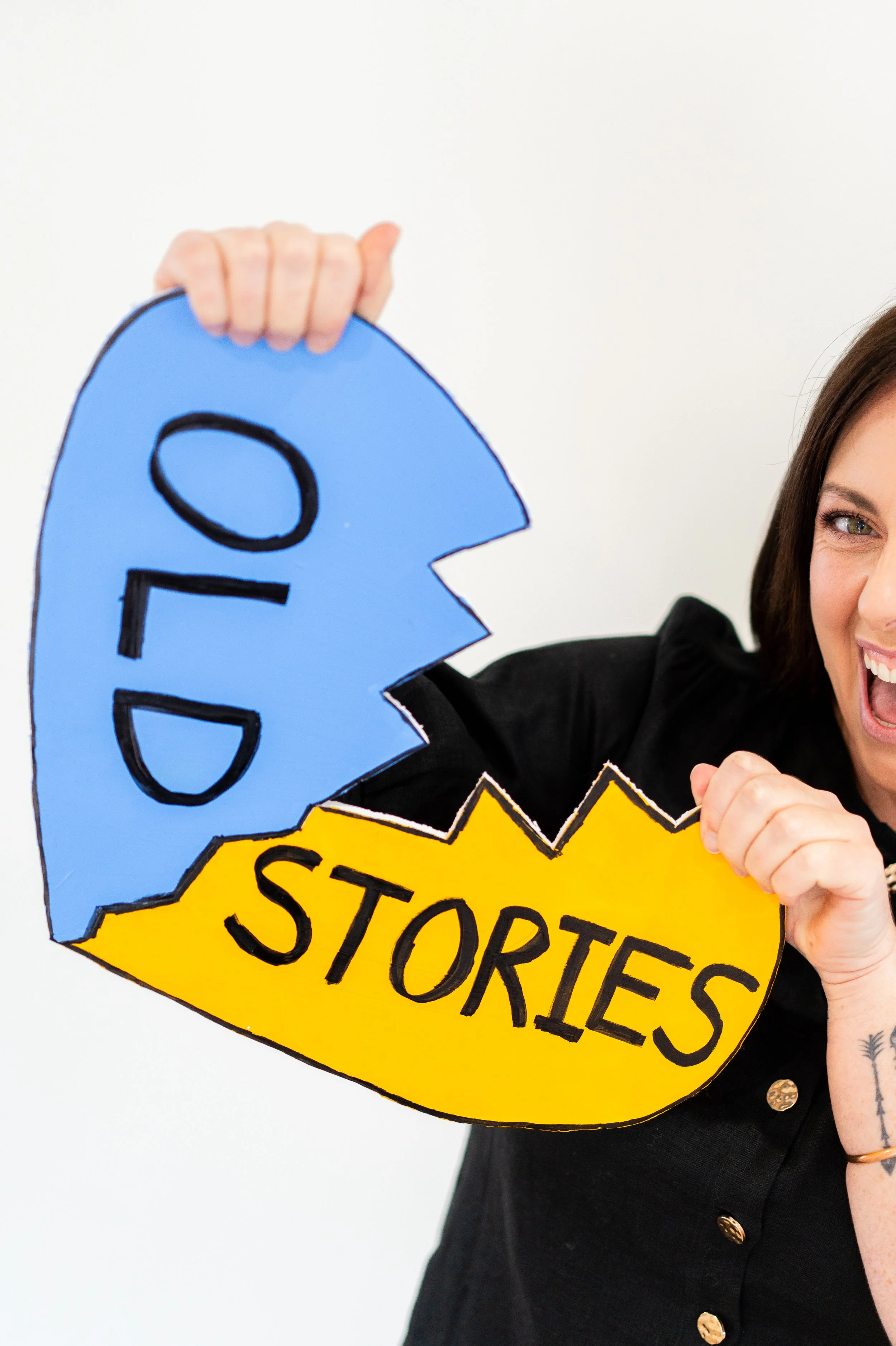 Woman holding up cutout signs tearing in half old stories in a playful manner.