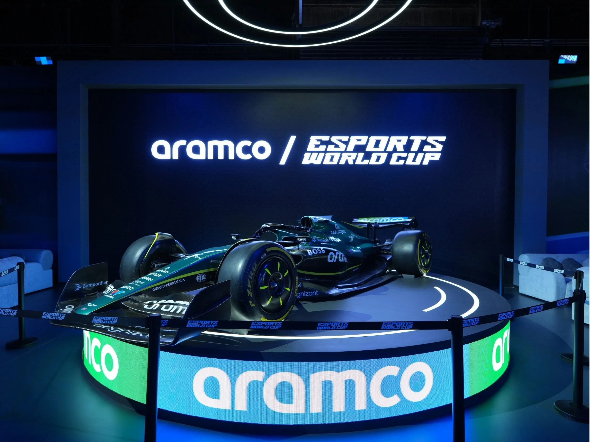 A race car on display at Aramco Esports World Cup event with a digital sign surrounding it, reading 'Aramco' and 'Esports World Cup'.  aramco, boulevard world, event, set design, construction