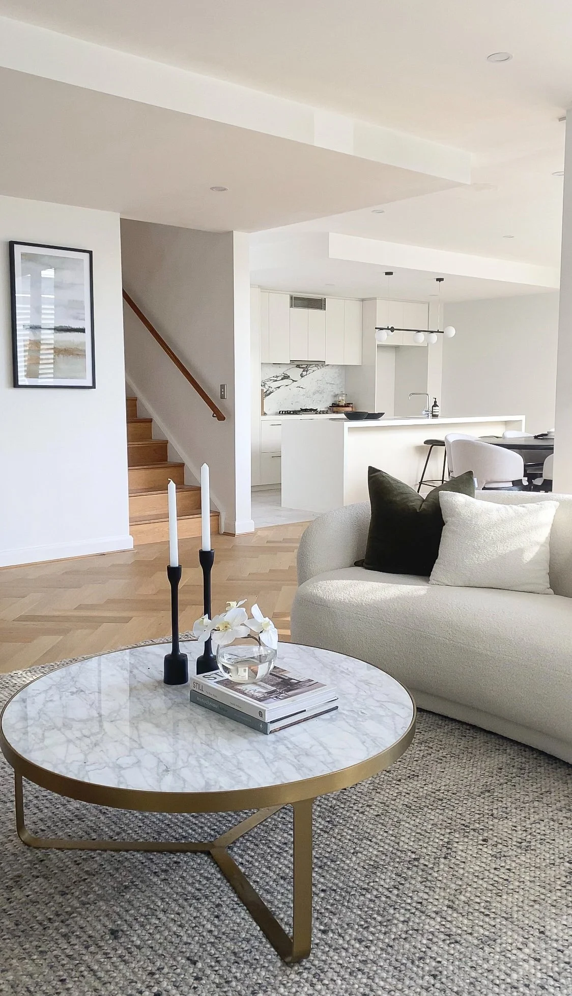 Modern interior setting with a velvet red chair, a white side table, a vase of colorful flowers, a coffee table with a book labeled 'Tom Ford,' and a gold bowl.