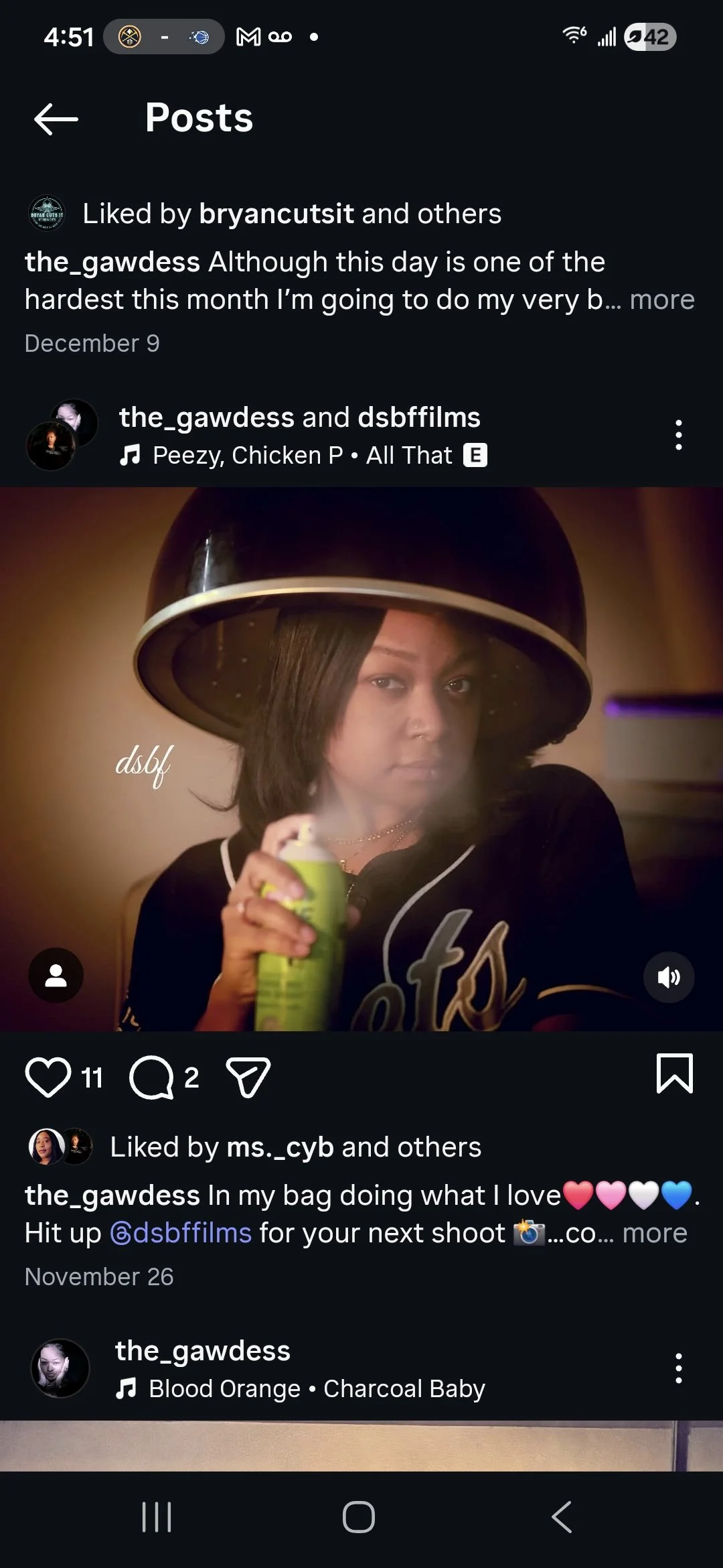 A woman in a hair salon sitting under a hair dryer hood, holding a spray can, with a serious expression.