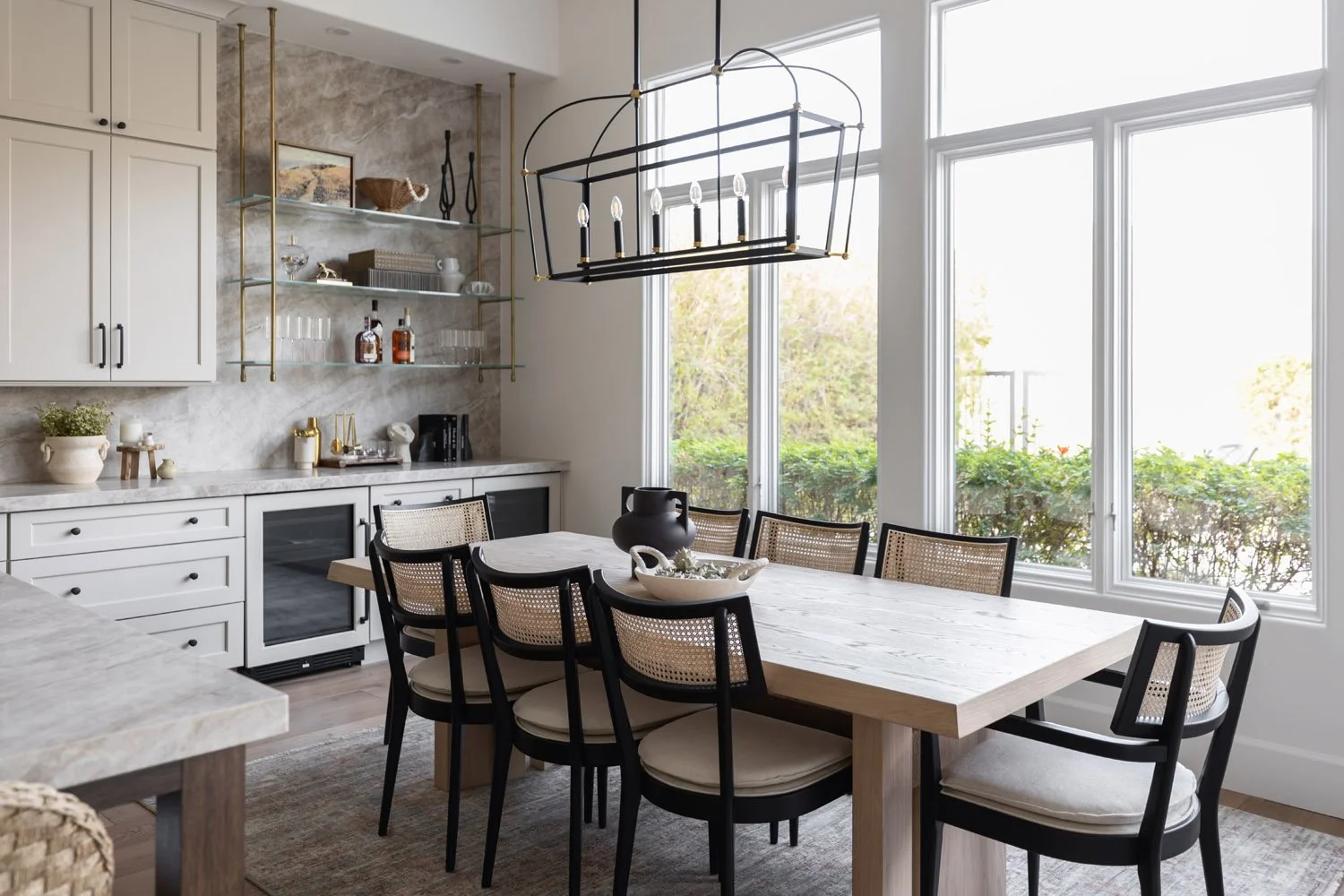 Dining room ith light oak table, cane chairs, and gold bar shelving