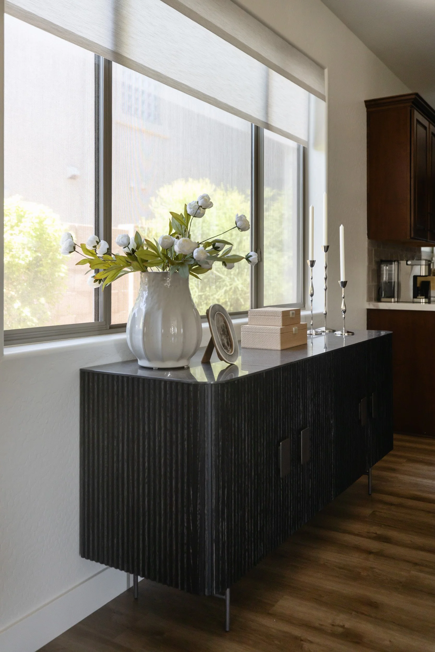 Black fluted sideboard with vase and greenery beside a window in a Phoenix dining nook