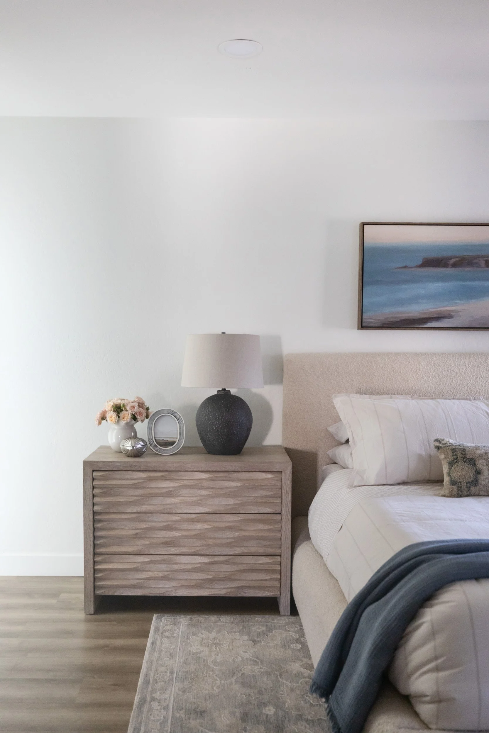 Wood nightstand with ceramic lamp beside the bed in an Arizona primary bedroom