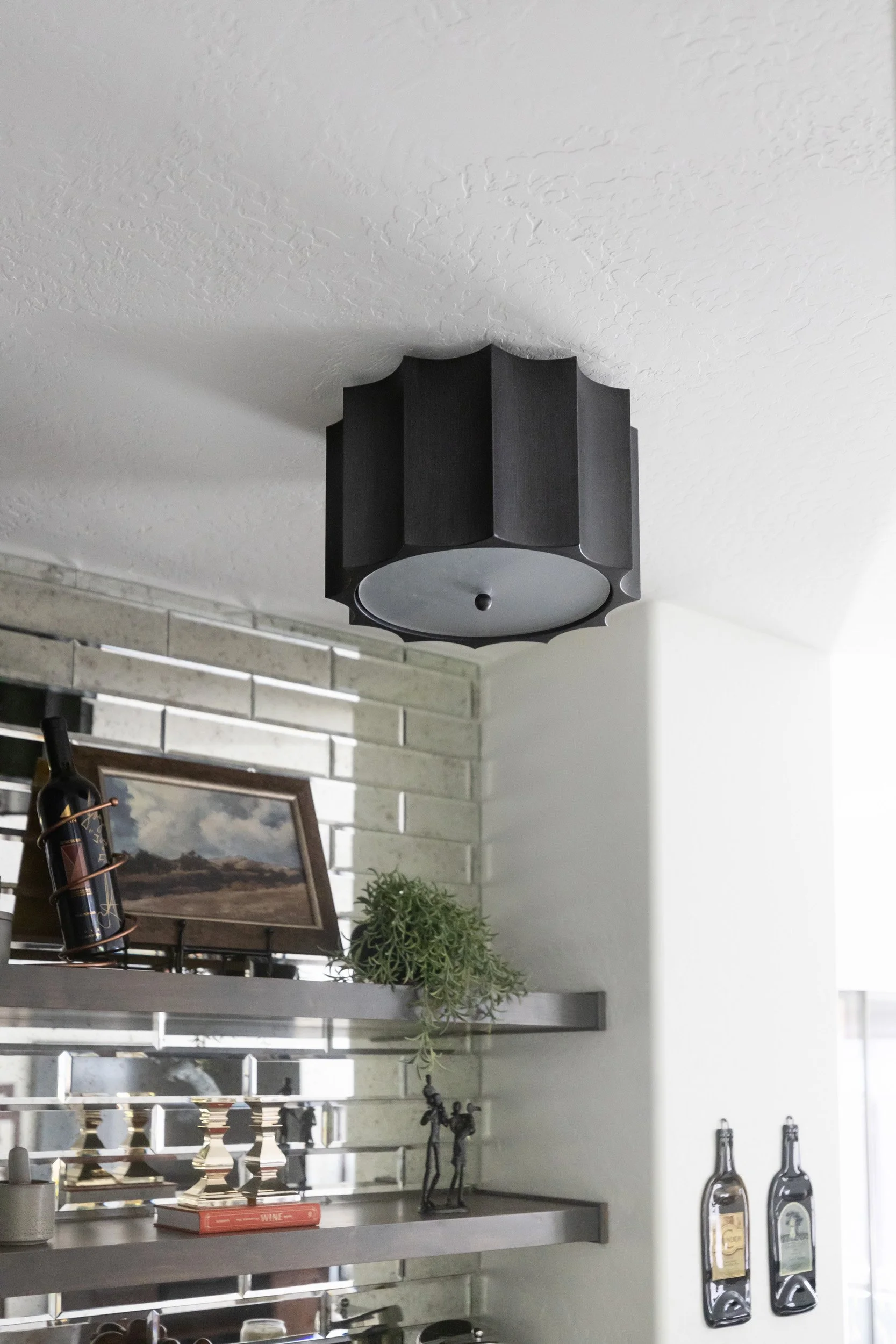 Black drum pendant above a wine bar with mirrored backsplash and open shelves, Phoenix