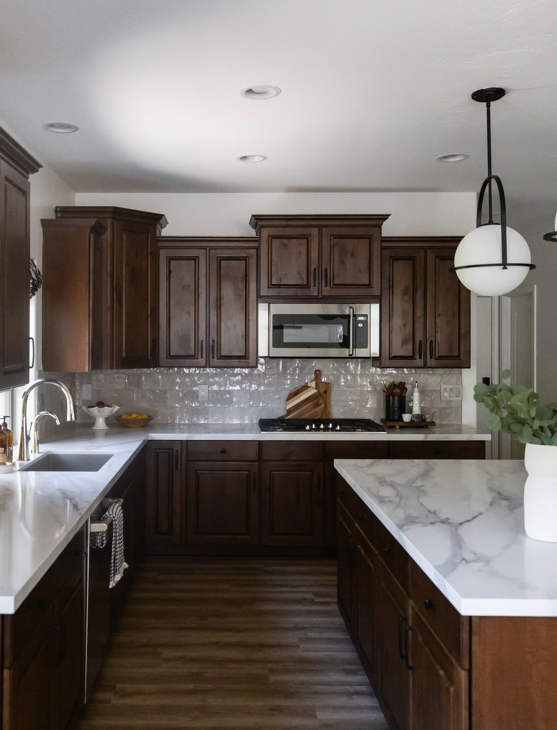 Kitchen island and globe pendant light beside dark wood cabinetry in an Arizona home