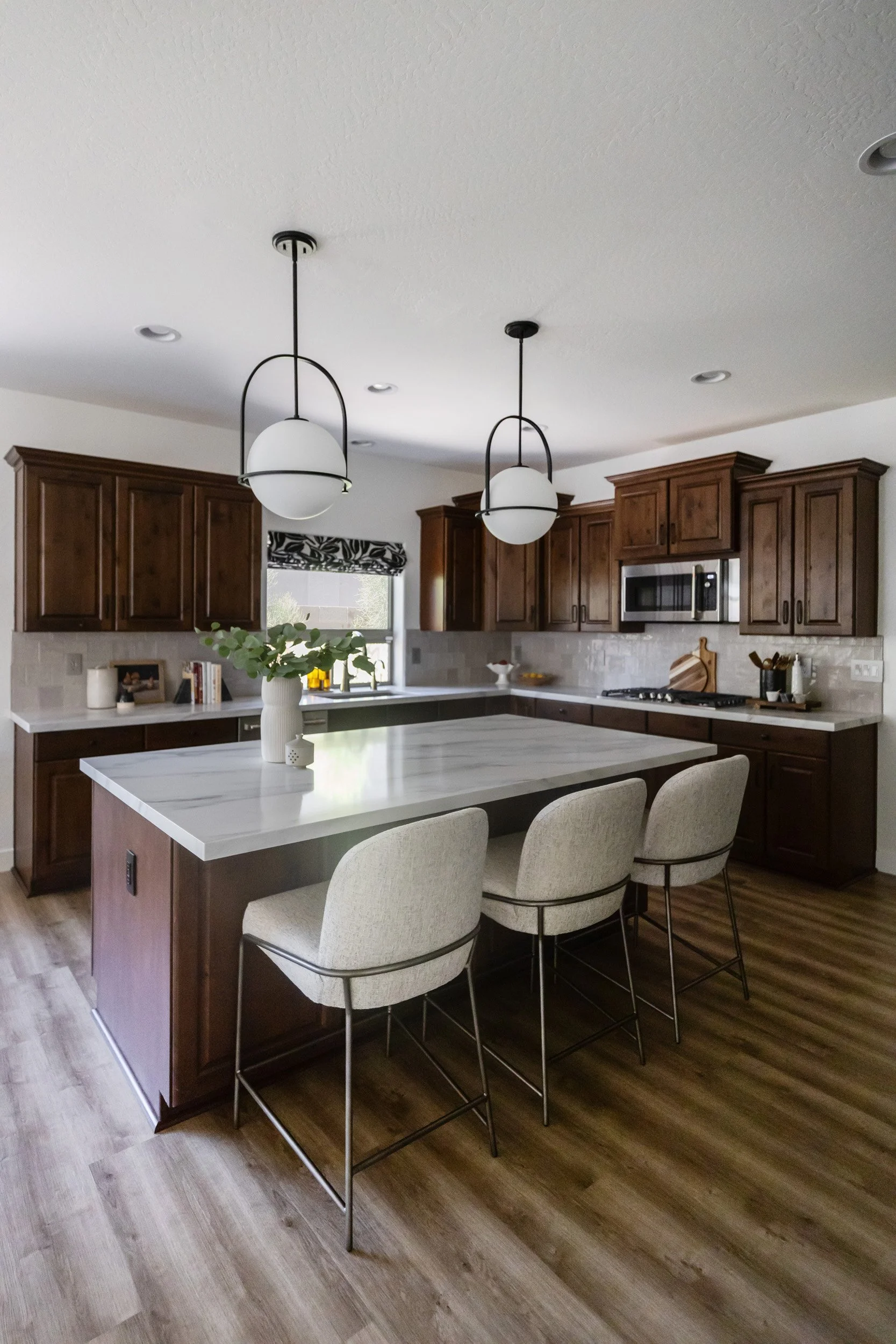 Kitchen with marble island, white counter stools and globe pendant lights in Desert Ridge, Phoenix