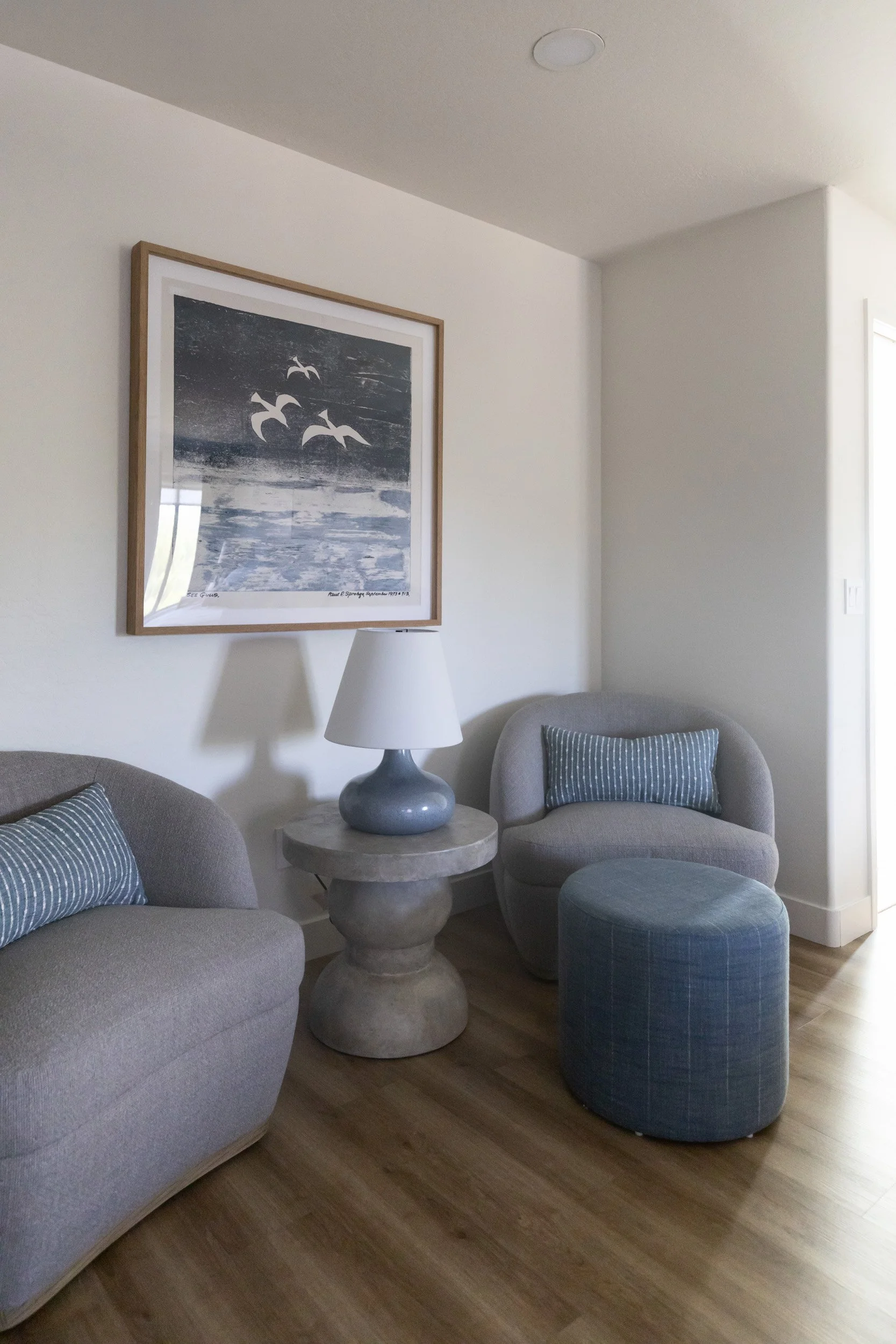 Two blue swivel chairs and an ottoman beneath framed art in a Desert Ridge primary bedroom