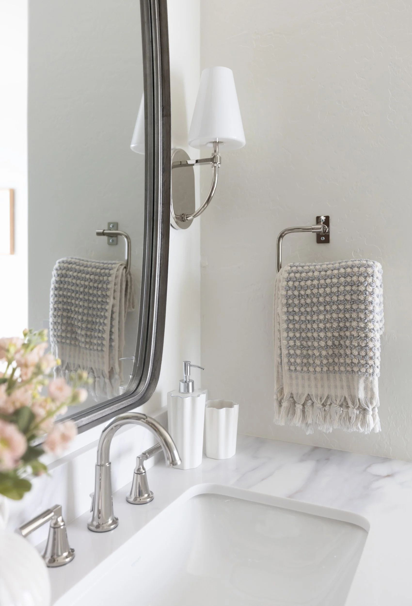 Marble vanity with nickel faucet, rounded mirror and woven towel in Desert Ridge