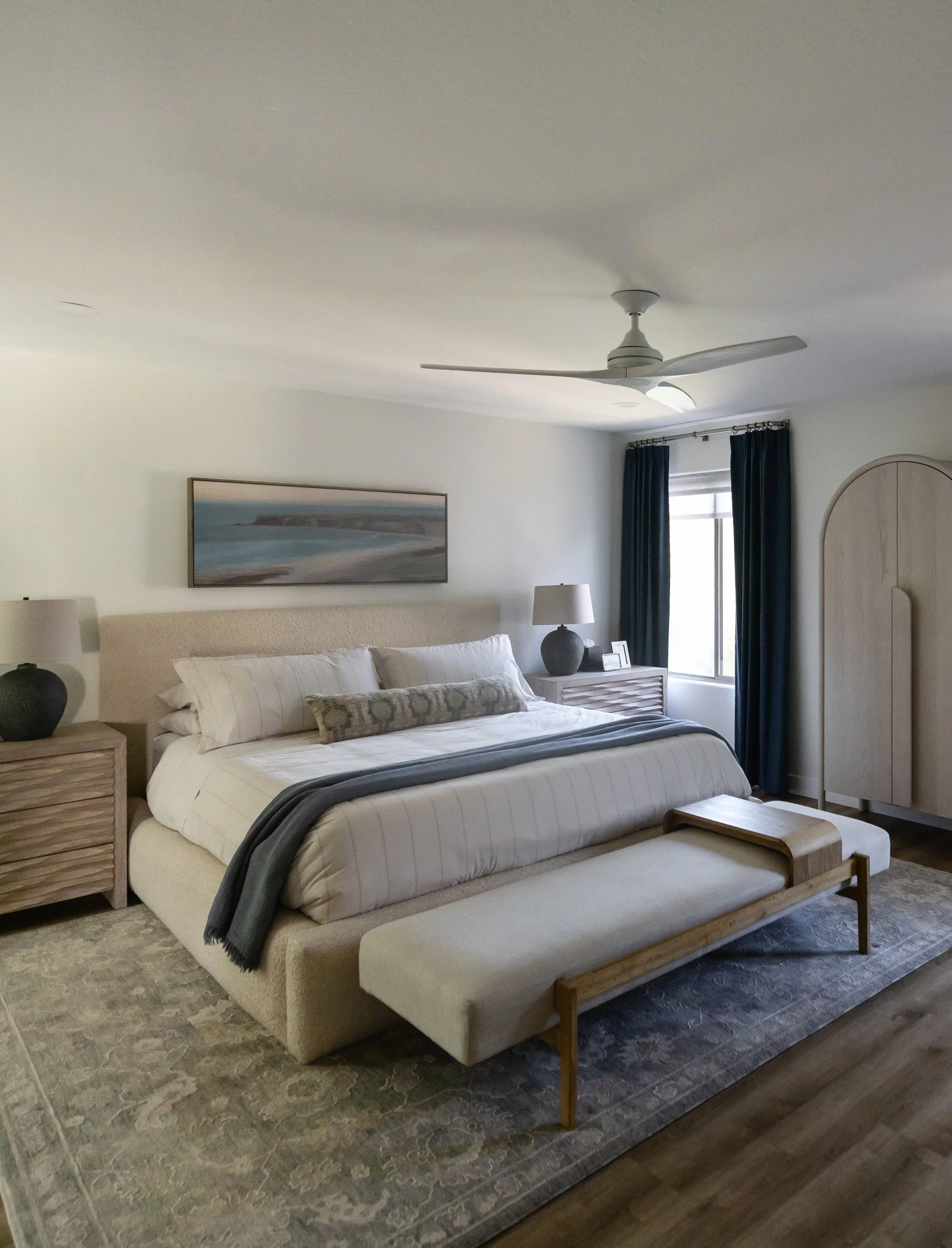 Primary bedroom with upholstered bed, bench, ceiling fan and blue accents in Desert Ridge