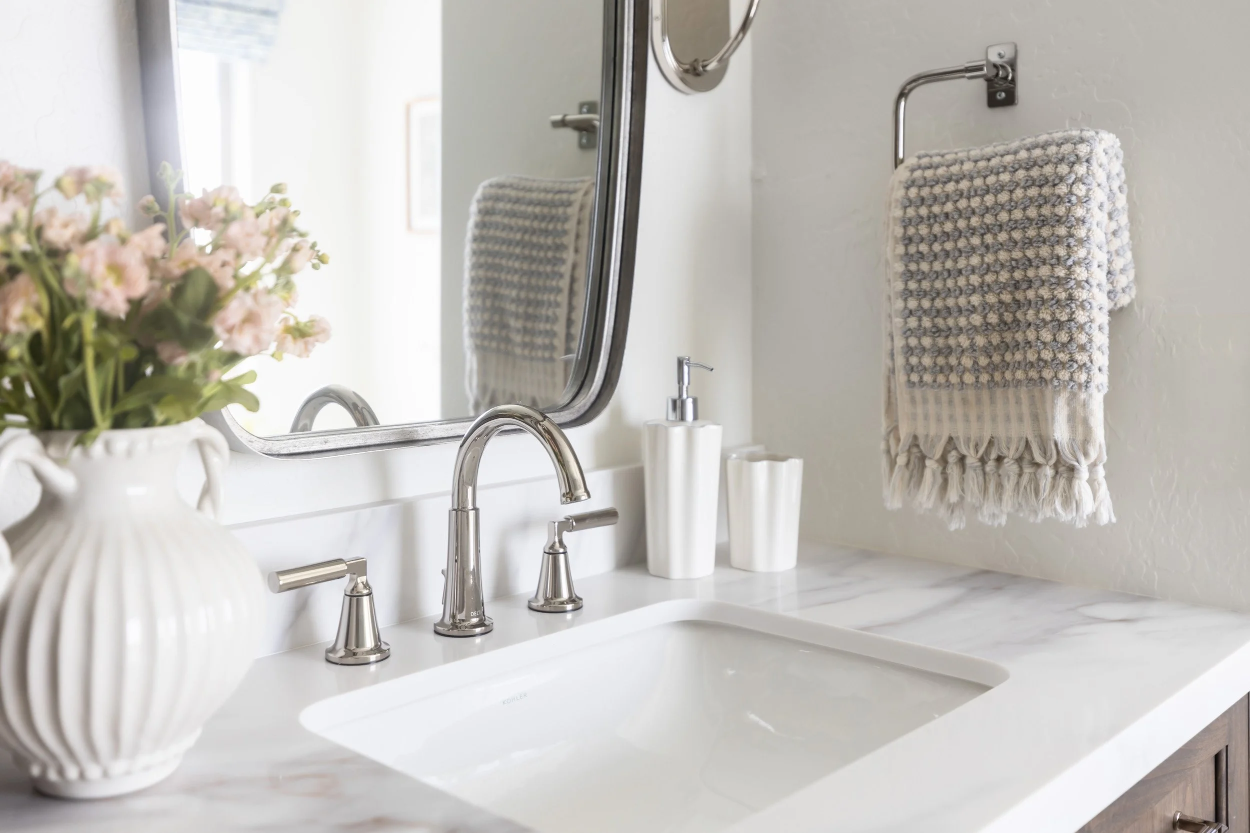 Undermount sink, nickel faucet and ribbed vase of flowers on a marble vanity in Phoenix