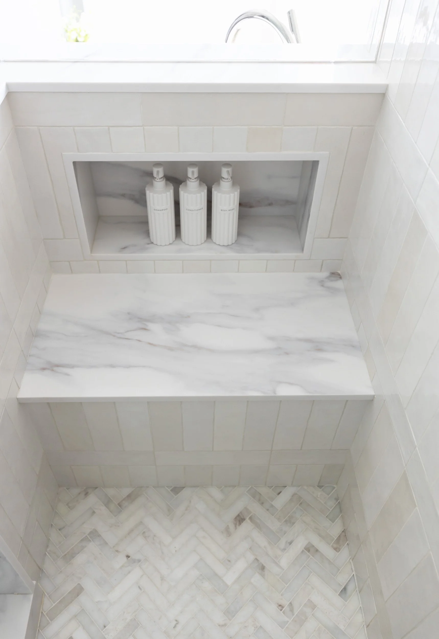Shower bench and recessed niche with marble tile in an Arizona primary bathroom