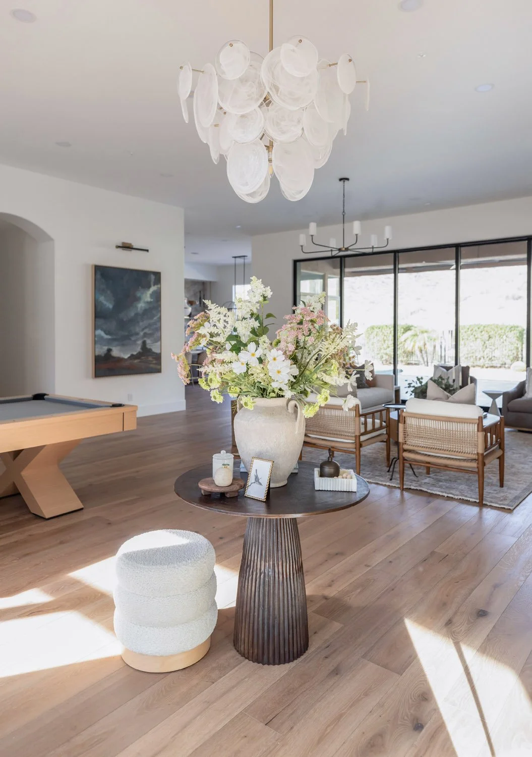 Interior design project of sunlit entry with round table, sculptural decor, and boucle ottoman in Scottsdale