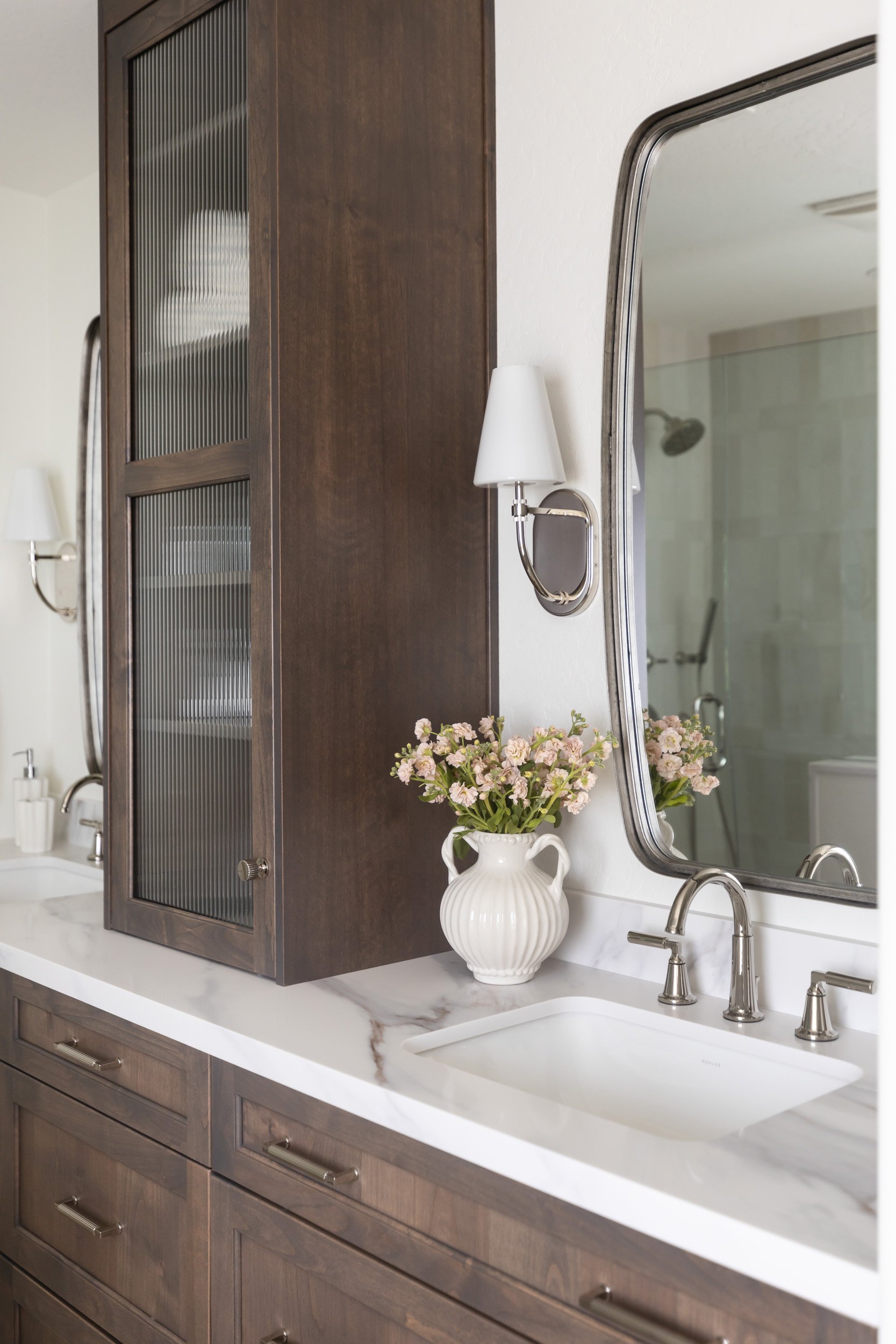Bathroom vanity with marble countertop, rounded mirror and sconce in Desert Ridge