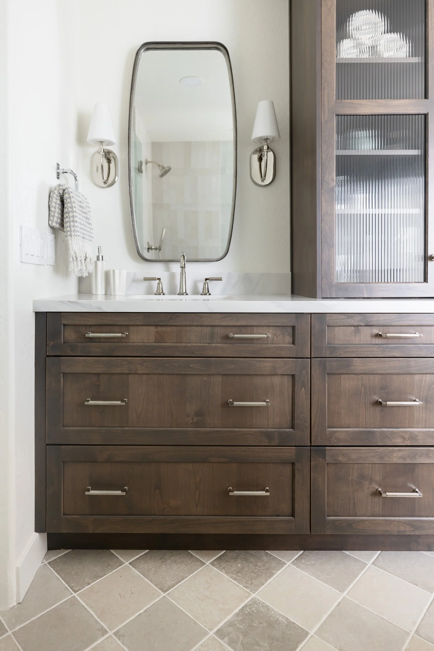 Dark wood bathroom vanity with marble top, mirror and sconces in Phoenix, Arizona