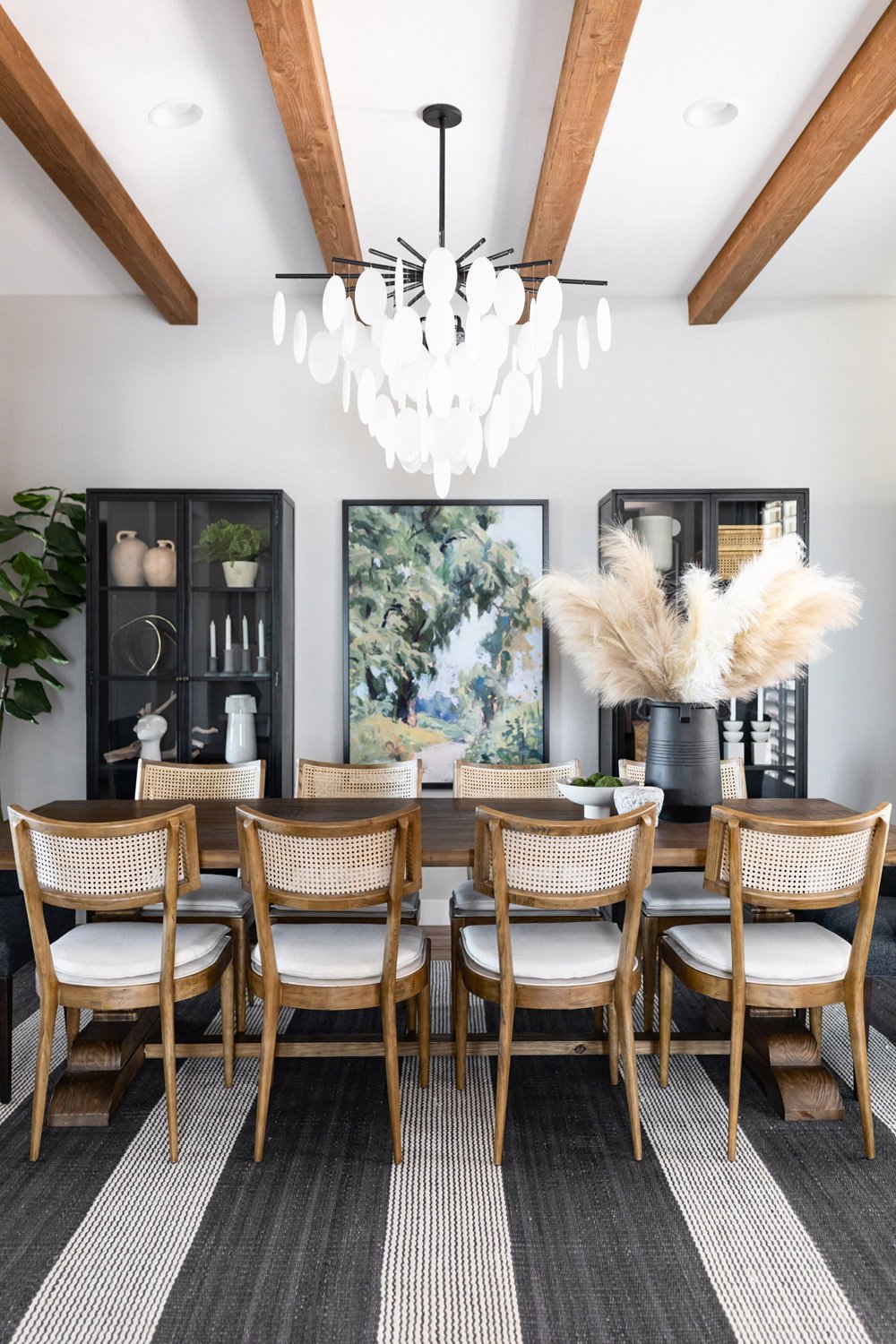 Dining room with dark wood trestle table, cane dining chairs and petal chandelier