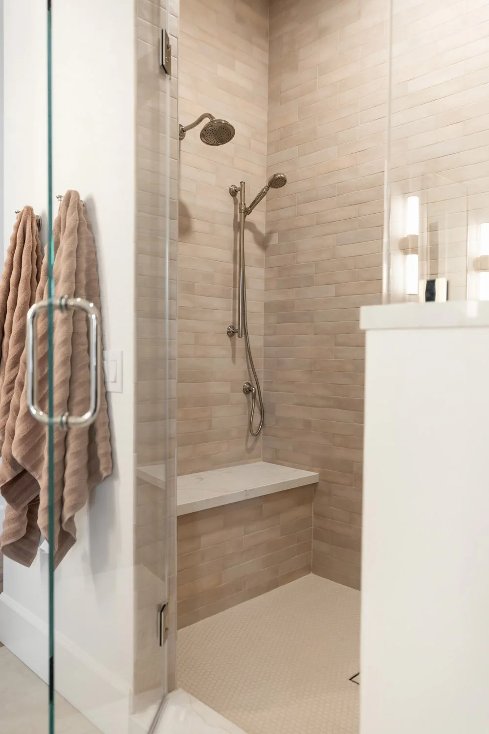 Shower with bench, handheld and rain fixtures, and warm neutral tile in Scottsdale home
