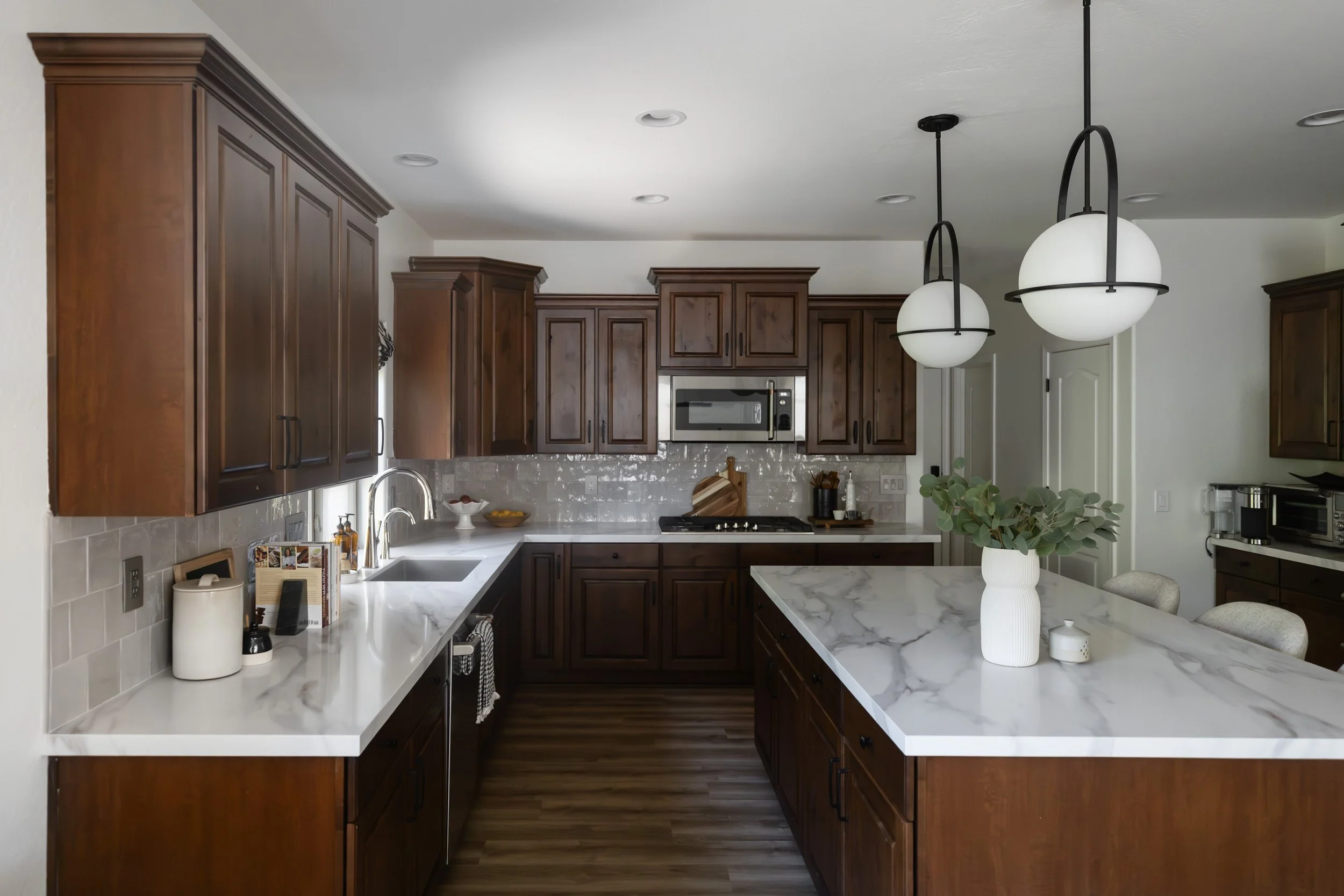 Kitchen with dark wood cabinets, white marble countertops and a large island in a Phoenix home