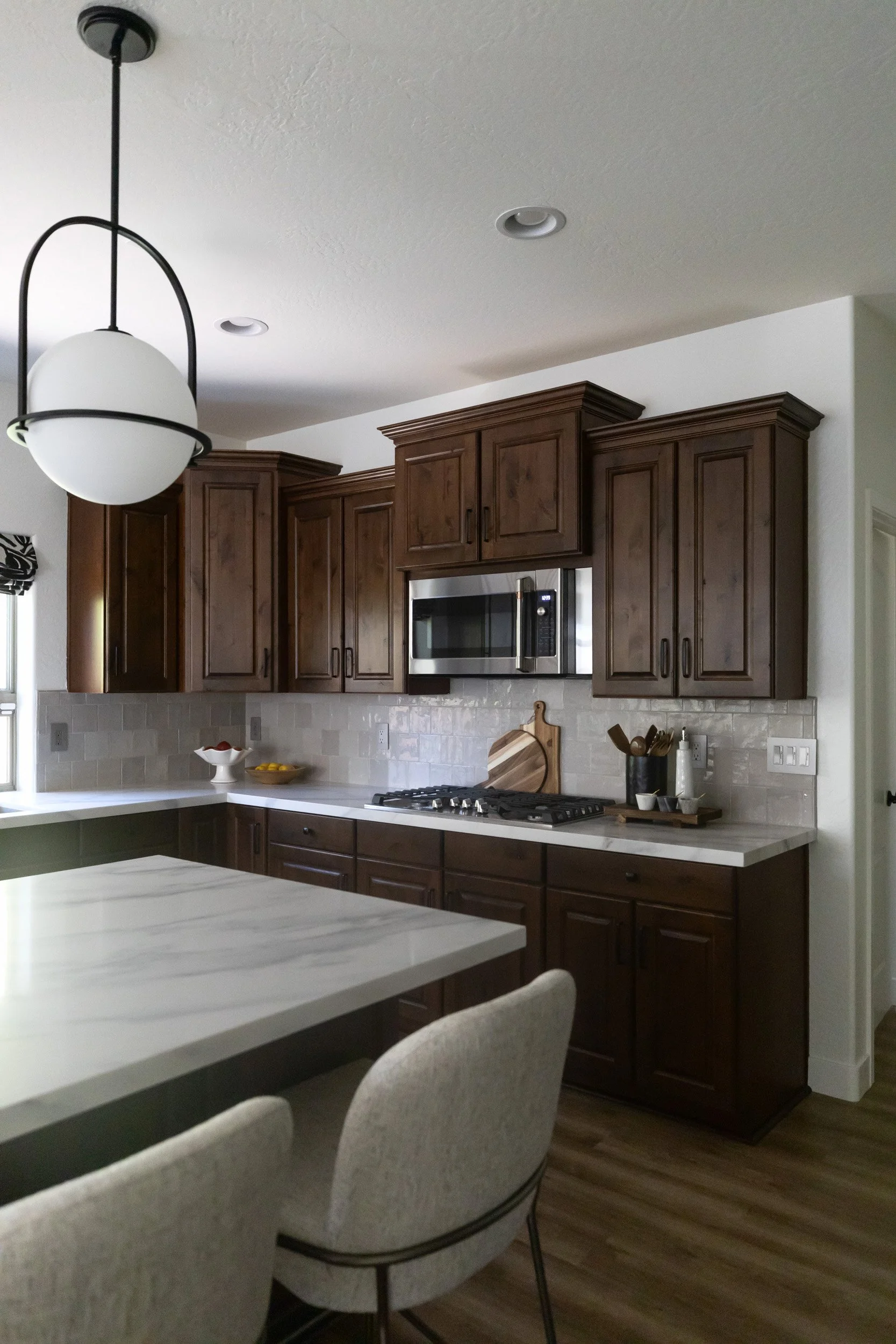 Globe pendant light above the kitchen island with dark wood cabinets behind, Phoenix, AZ