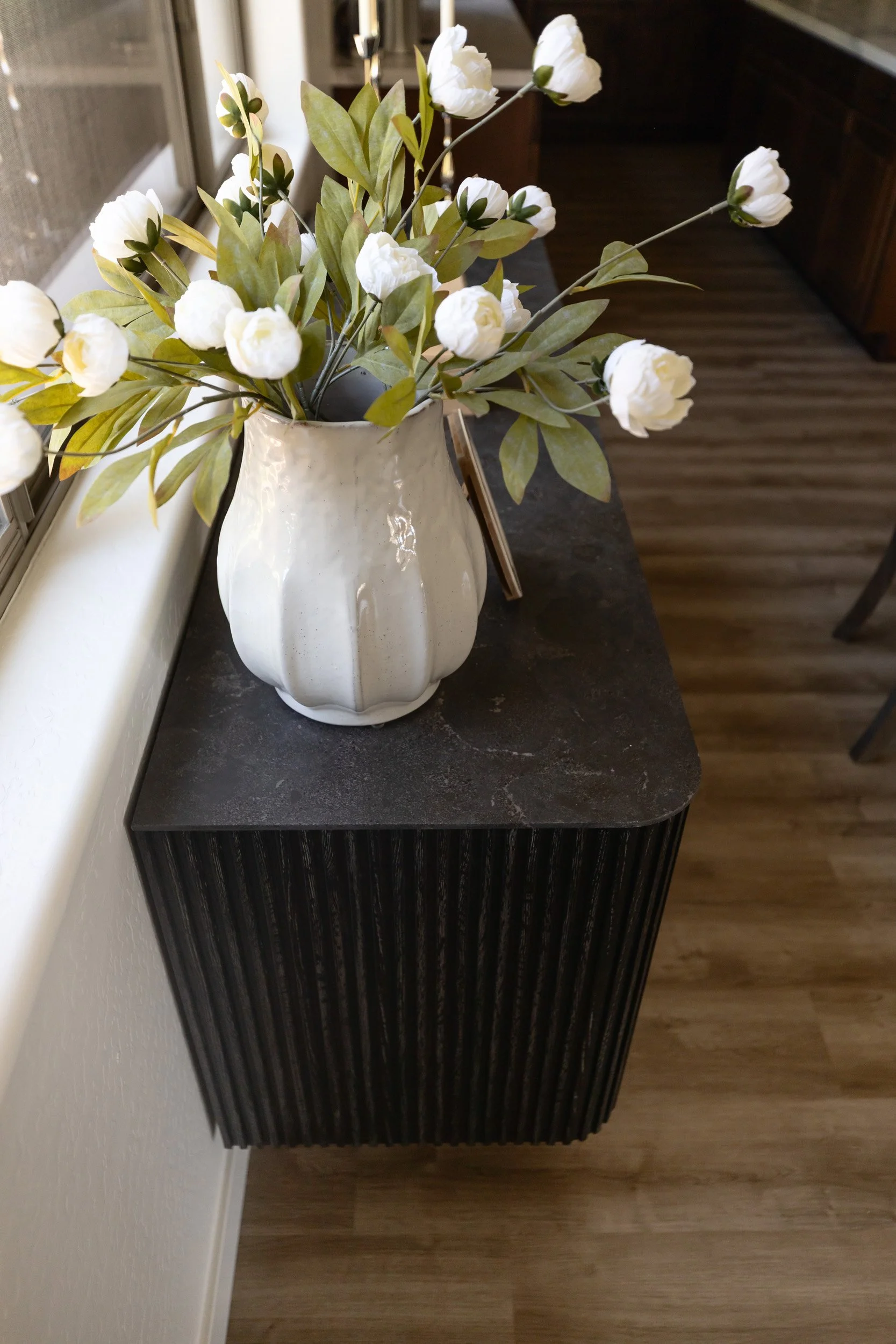 White tulips in a ceramic vase on a black fluted sideboard, Desert Ridge dining nook
