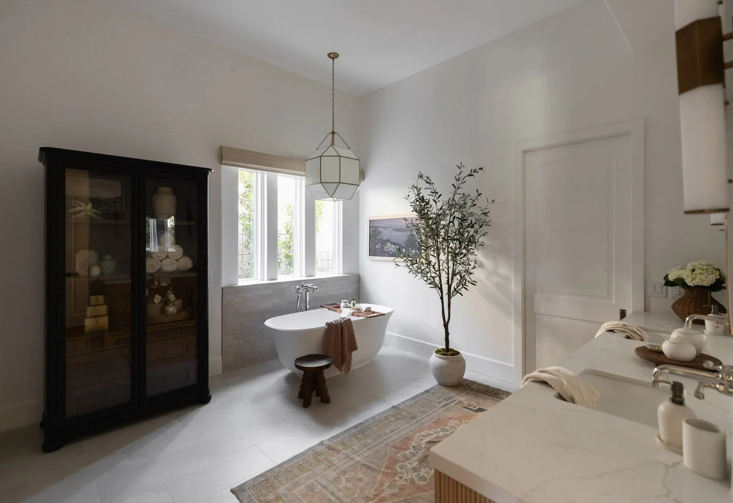 Scottsdale spa-like primary bath with display cabinets, olive tree, and soaking zone.