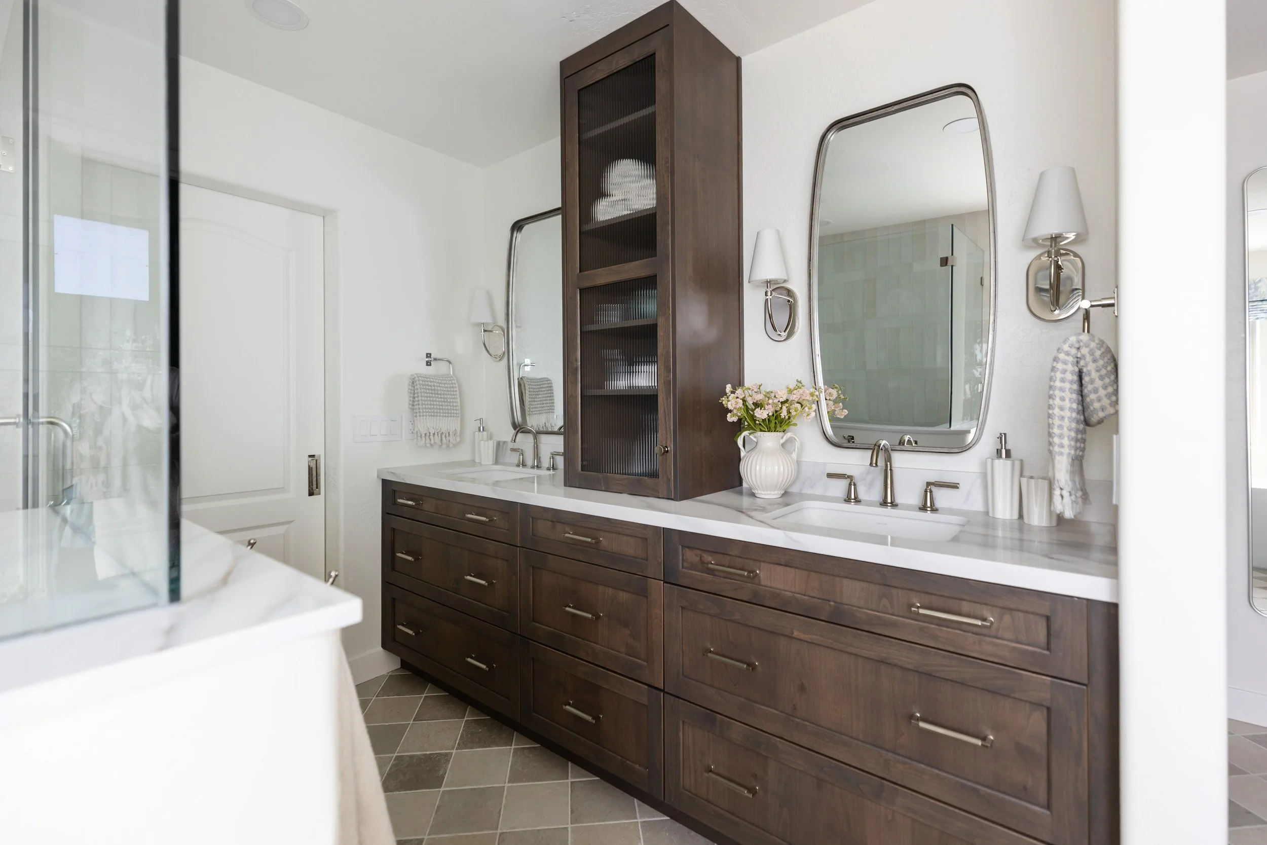 Primary bathroom double vanity with dark wood cabinets, marble top and rounded mirrors, Phoenix, AZ