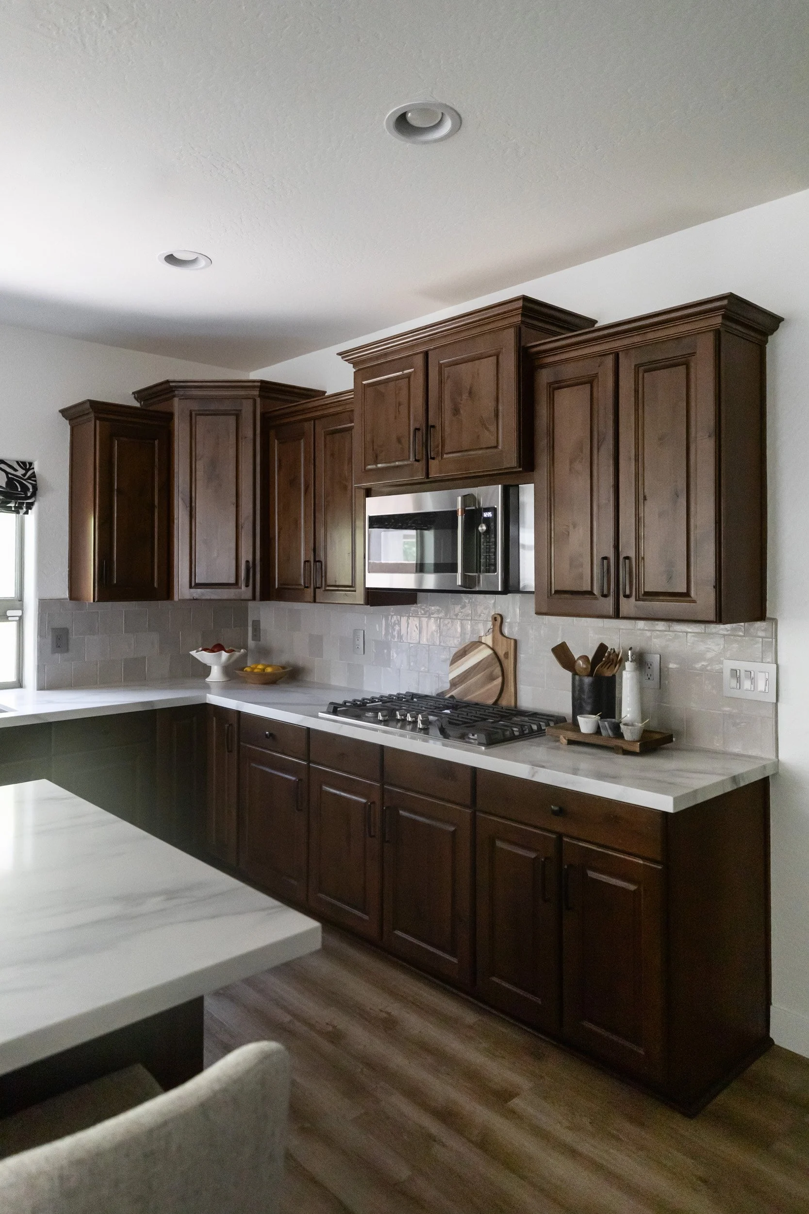 Kitchen range wall with dark wood cabinets, stainless steel microwave and tile backsplash, Desert Ridge