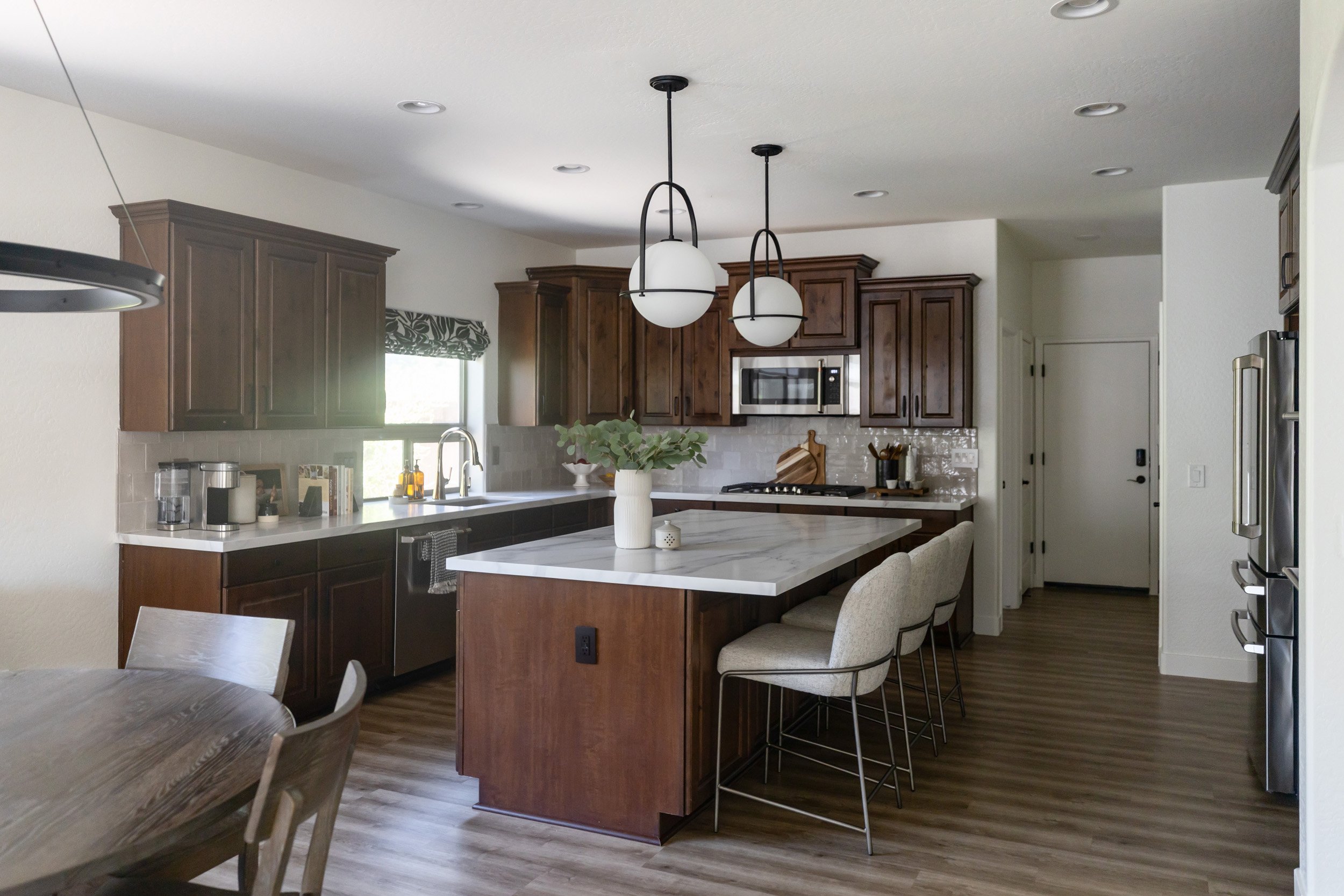 Open kitchen with marble island, white counter stools and dining table in Phoenix, Arizona