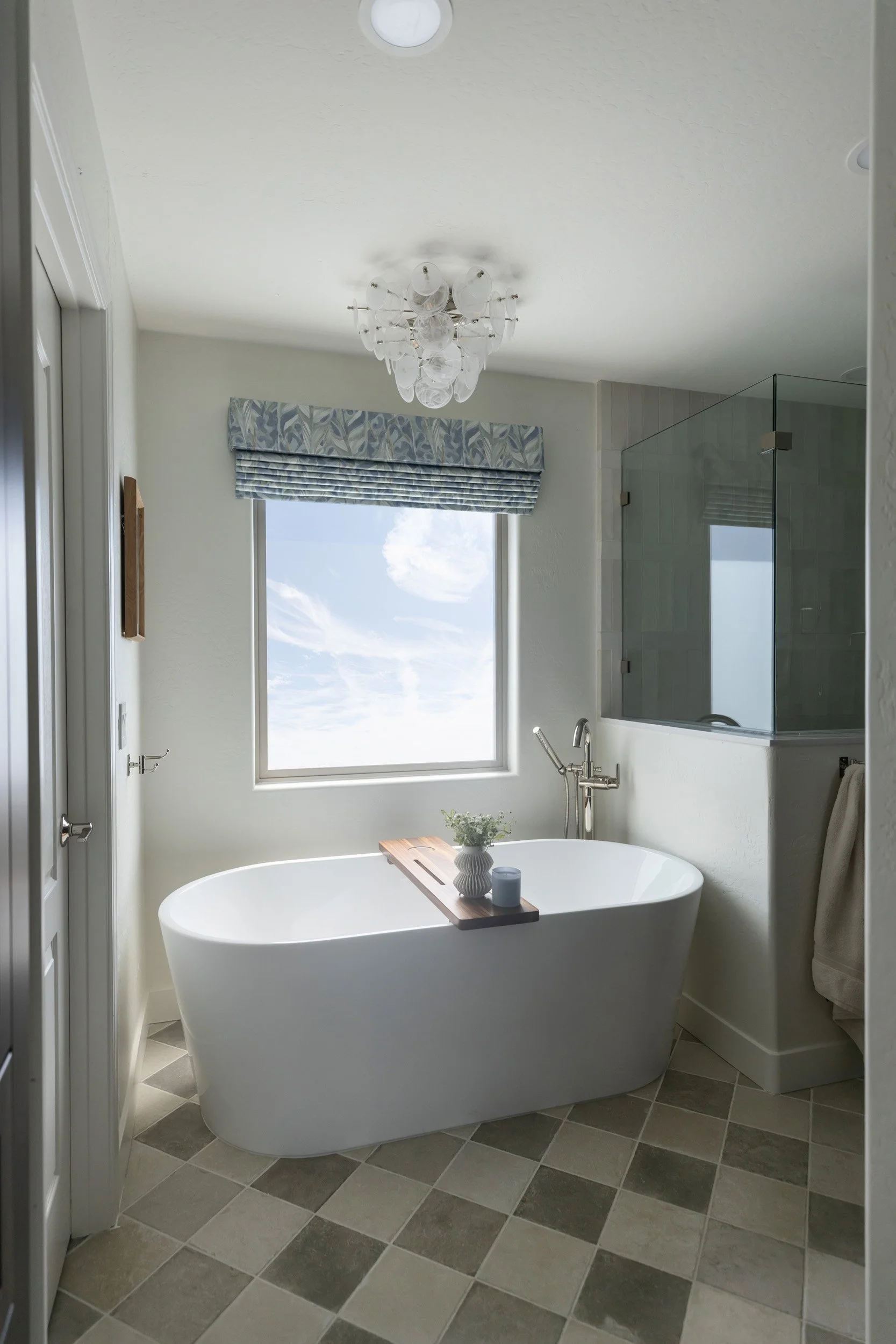 Freestanding tub beneath a window with chandelier and checkered tile floor, Desert Ridge
