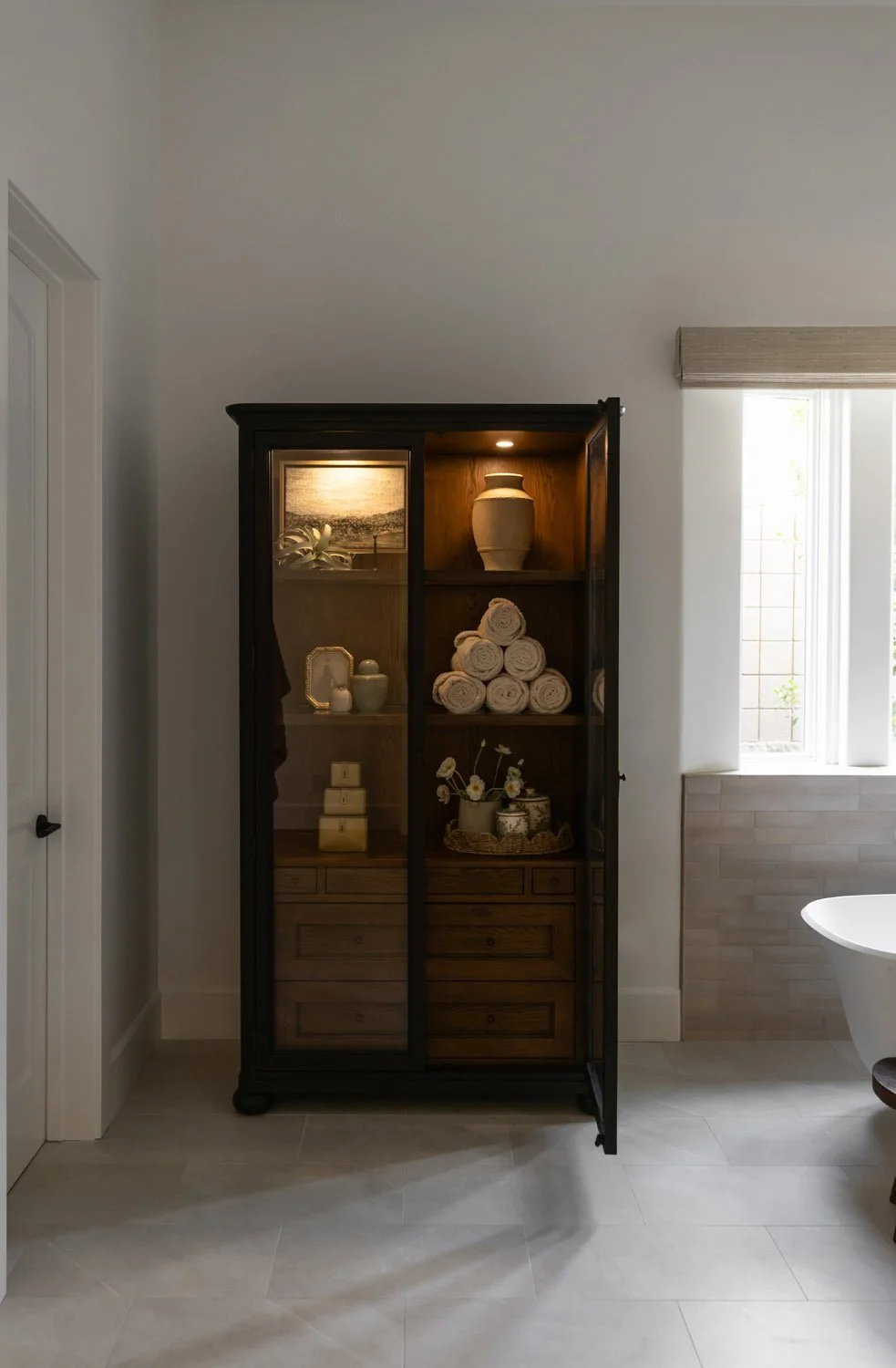 Interior design project including bathroom with glass-front cabinet, glass shelving, and styled towels in modern design.