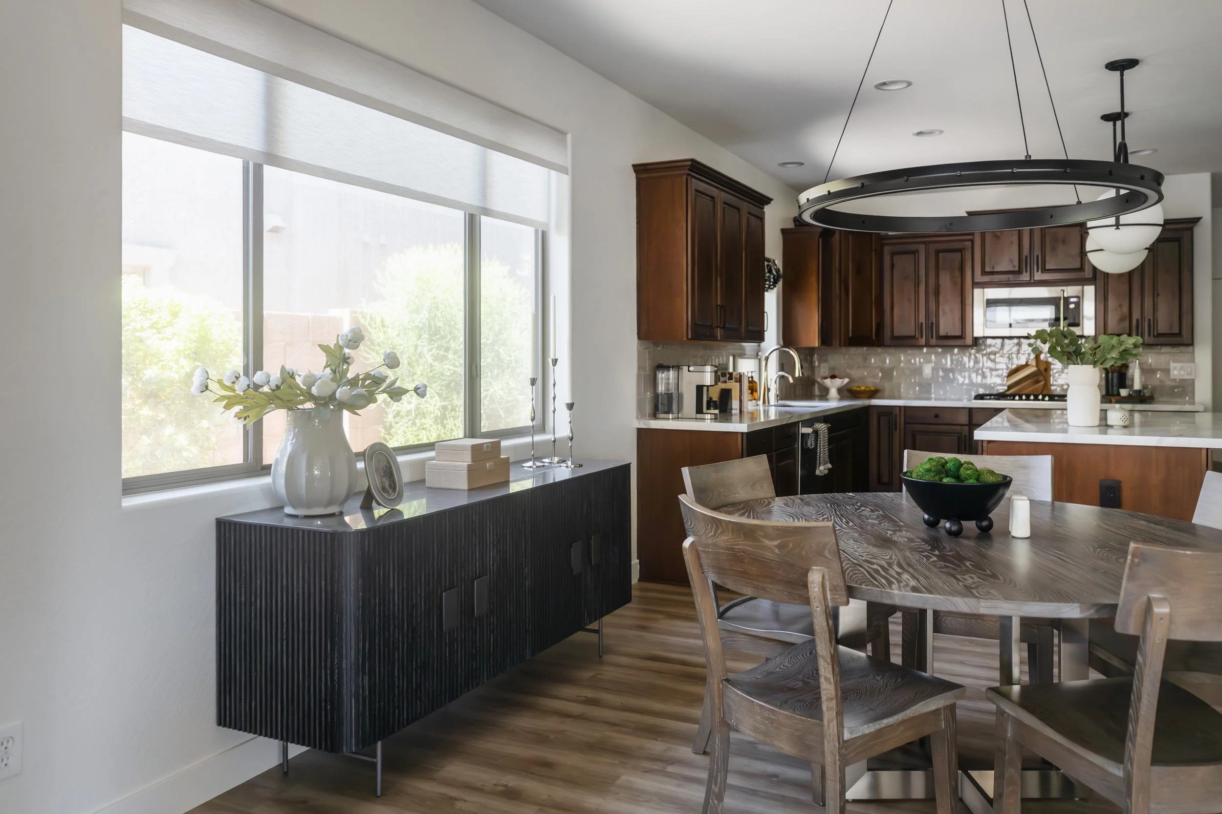 Dining nook with round table, wood chairs, ring chandelier and black sideboard in Desert Ridge