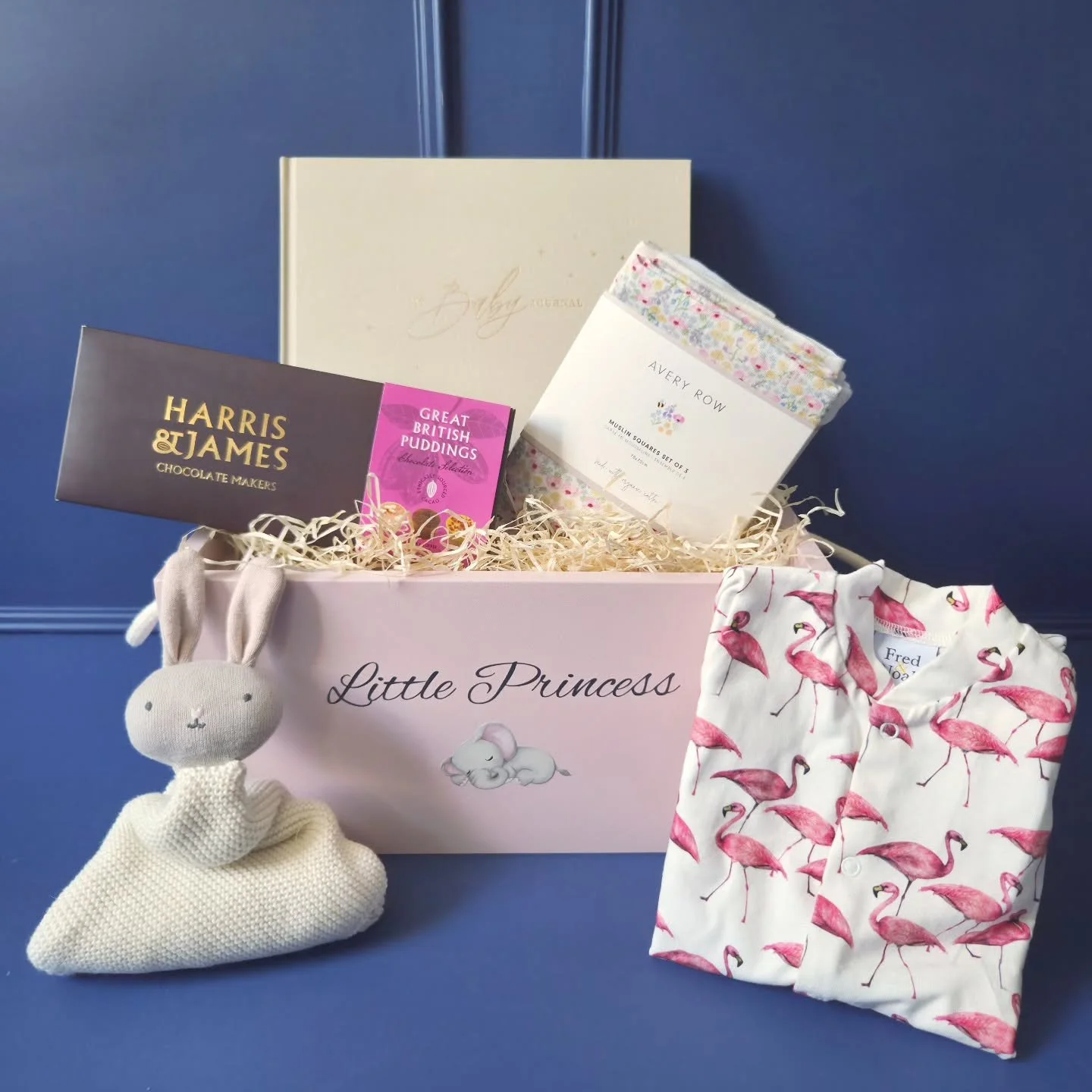 A charming wooden hamper, lovingly curated to welcome a little prince or princess into the world. Inside, gentle organic cotton treasures from Avery Row (As seen in Fortum &amp; Mason) offer comfort and softness &mdash; a cuddle cloth for precious sn