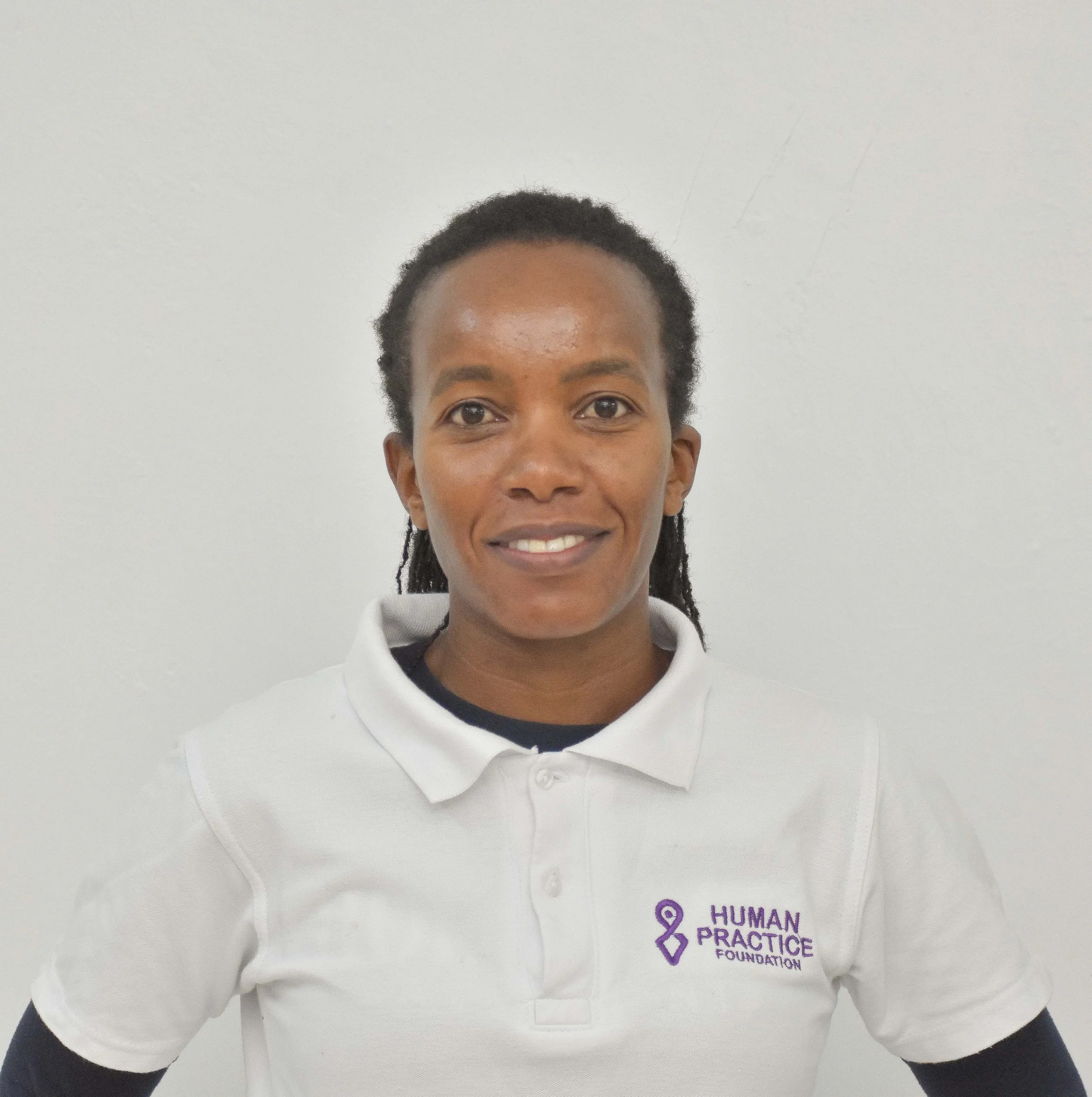 A professional man with gray hair wearing a dark suit and white shirt, standing indoors with a blurred background.