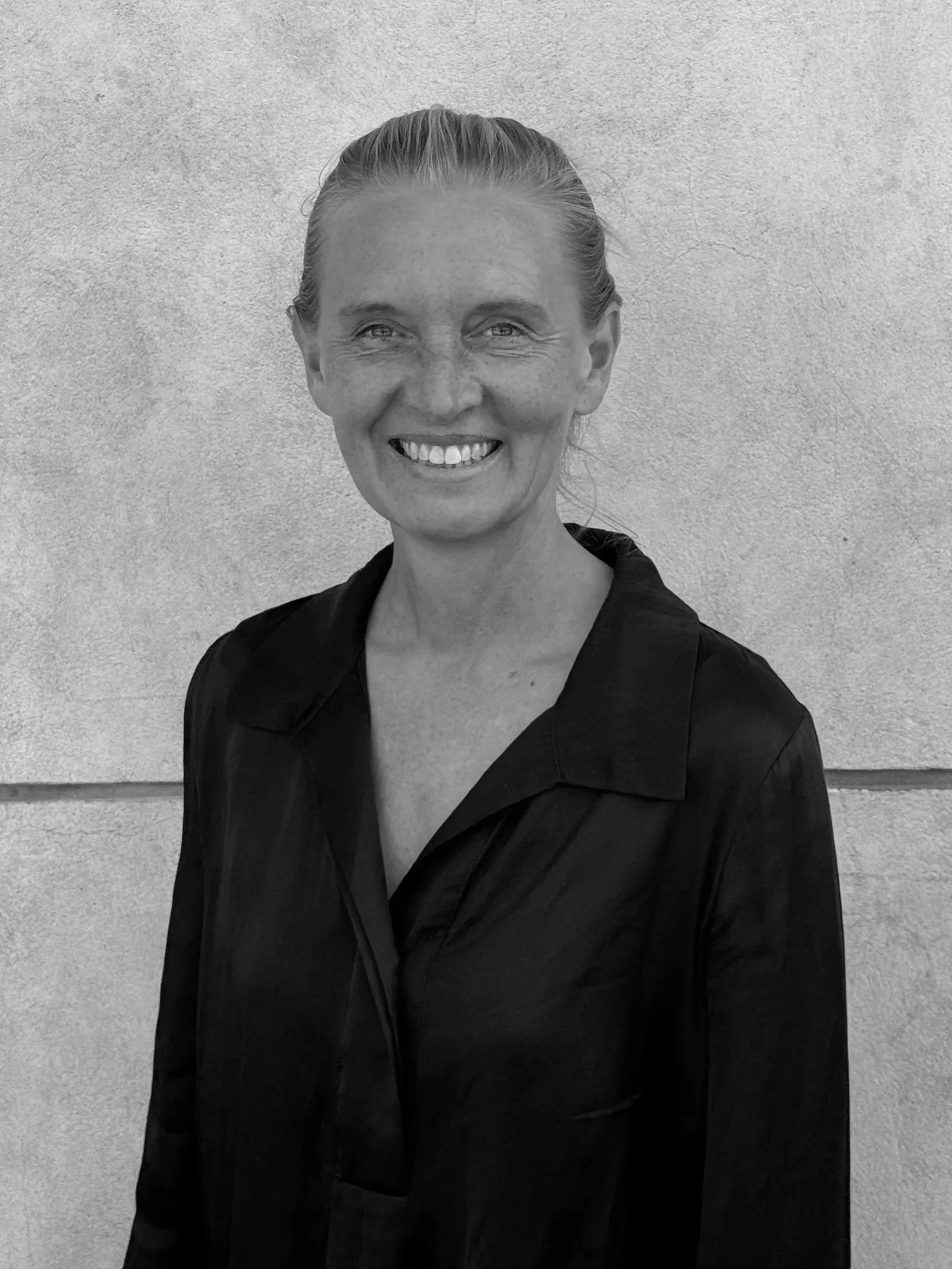 A professional headshot of a smiling man in a suit and tie against a textured blue background.