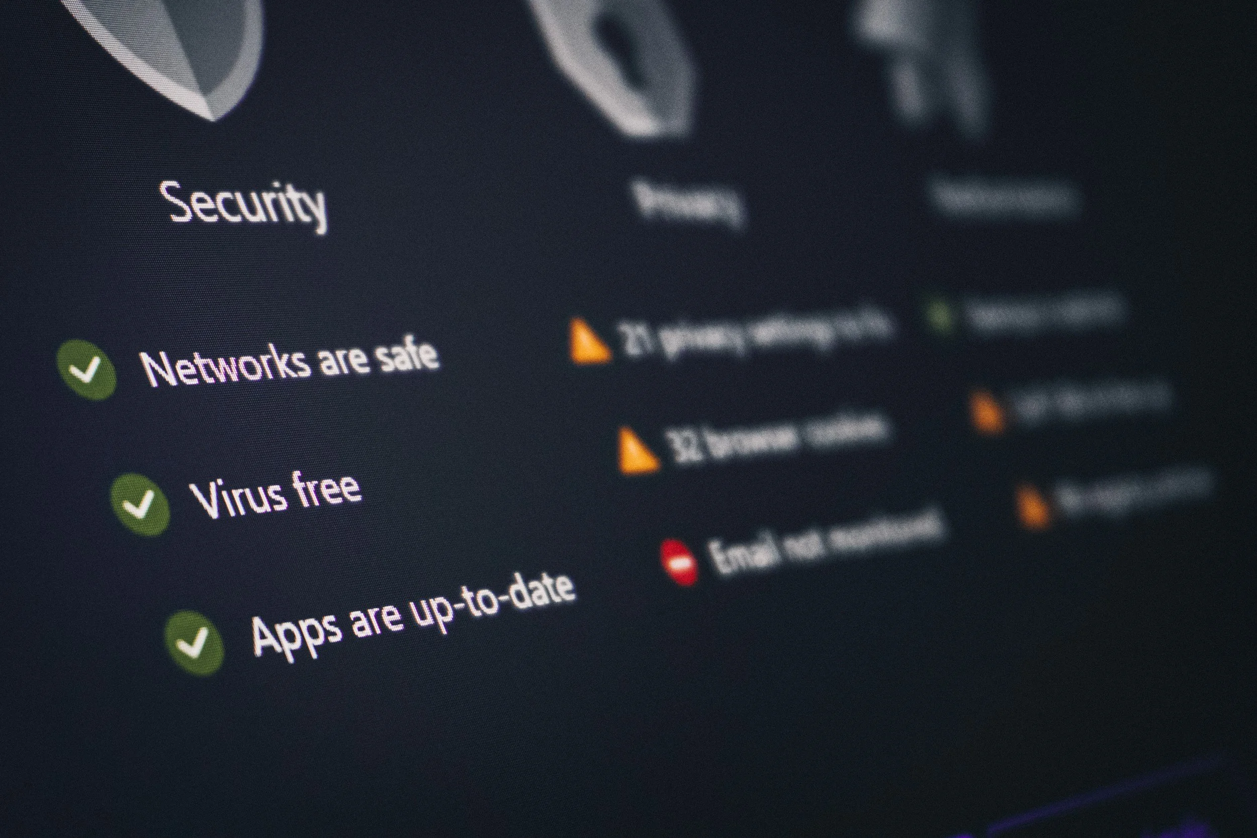 Close-up of a computer screen showing security status, with green checkmarks and text indicating secure and safe networks, virus-free status, and up-to-date apps.