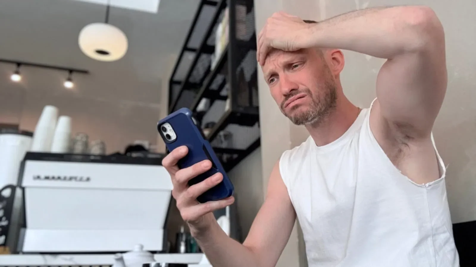 Gay man sitting alone looking at his phone, representing the loneliness of app-based socialising