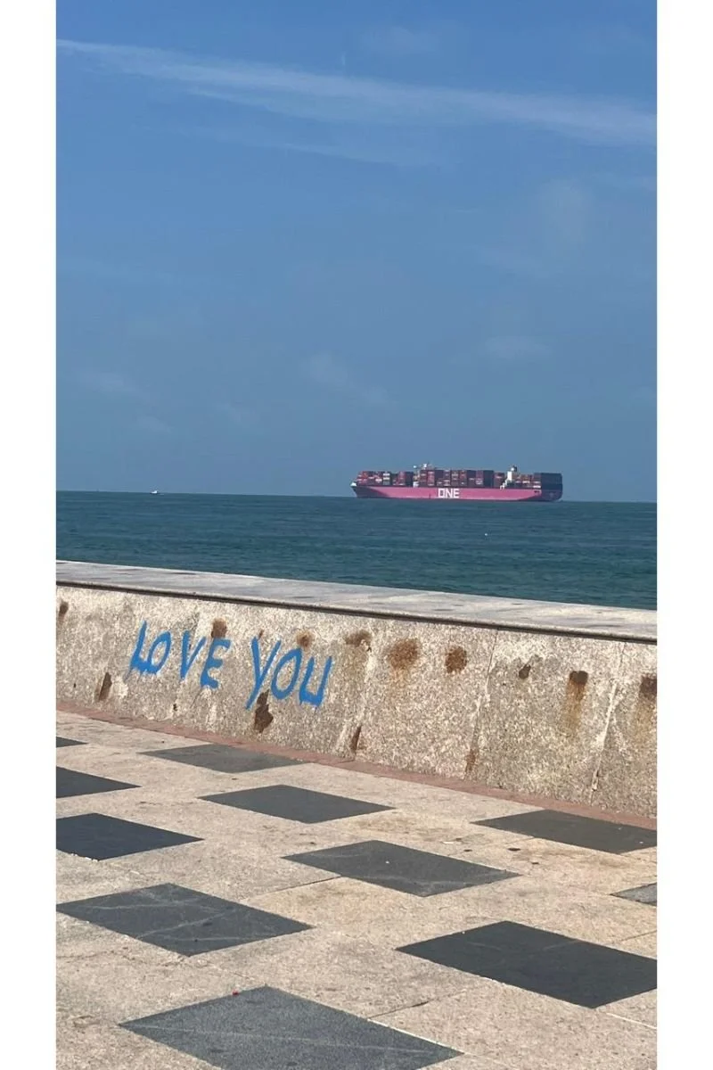 Love you graffiti on a wall in Vung Tau with a large pink container ship on the sea behind