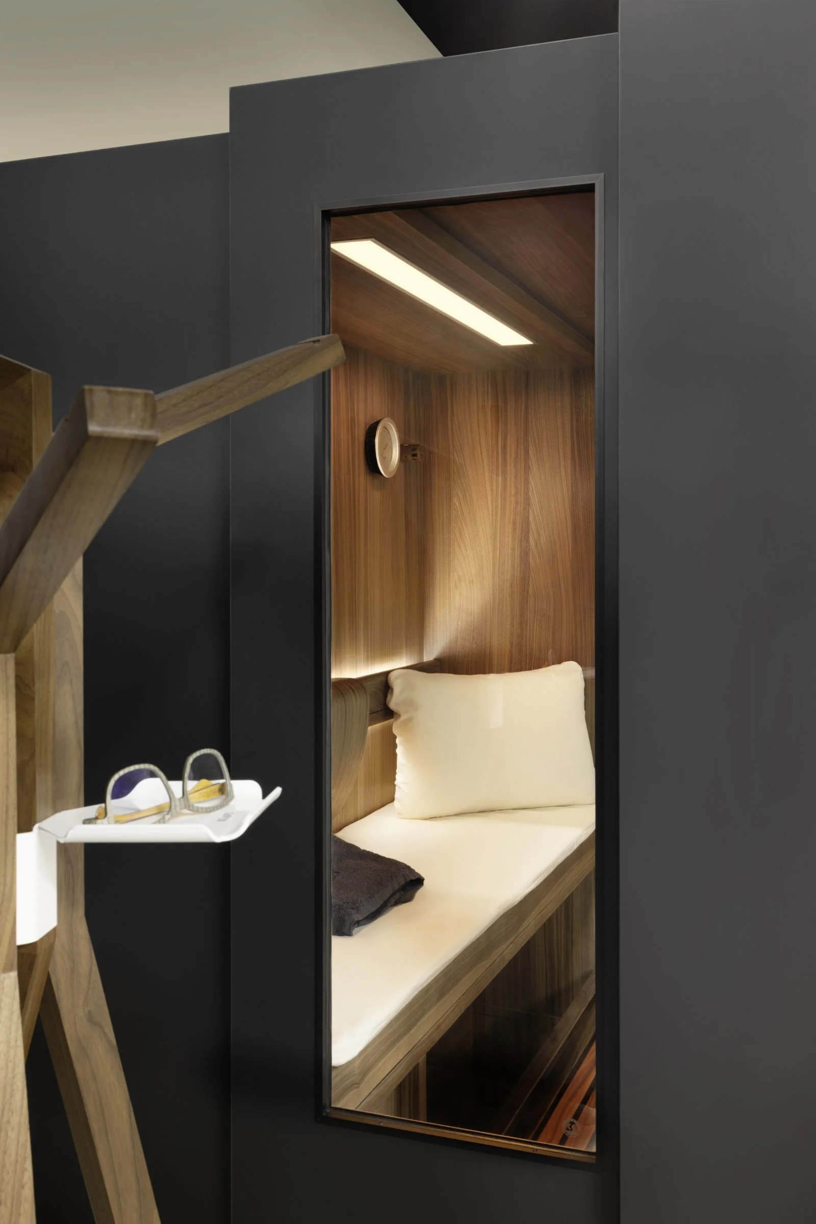 Diese Perspektive zeigt das innovative Industrial Design der kompakten Sauna im Ruhezustand, bei dem sie sich als elegantes Möbelstück mit edler Holzinnenausstattung und integrierter Beleuchtung nahtlos in moderne Wohnkonzepte einfügt