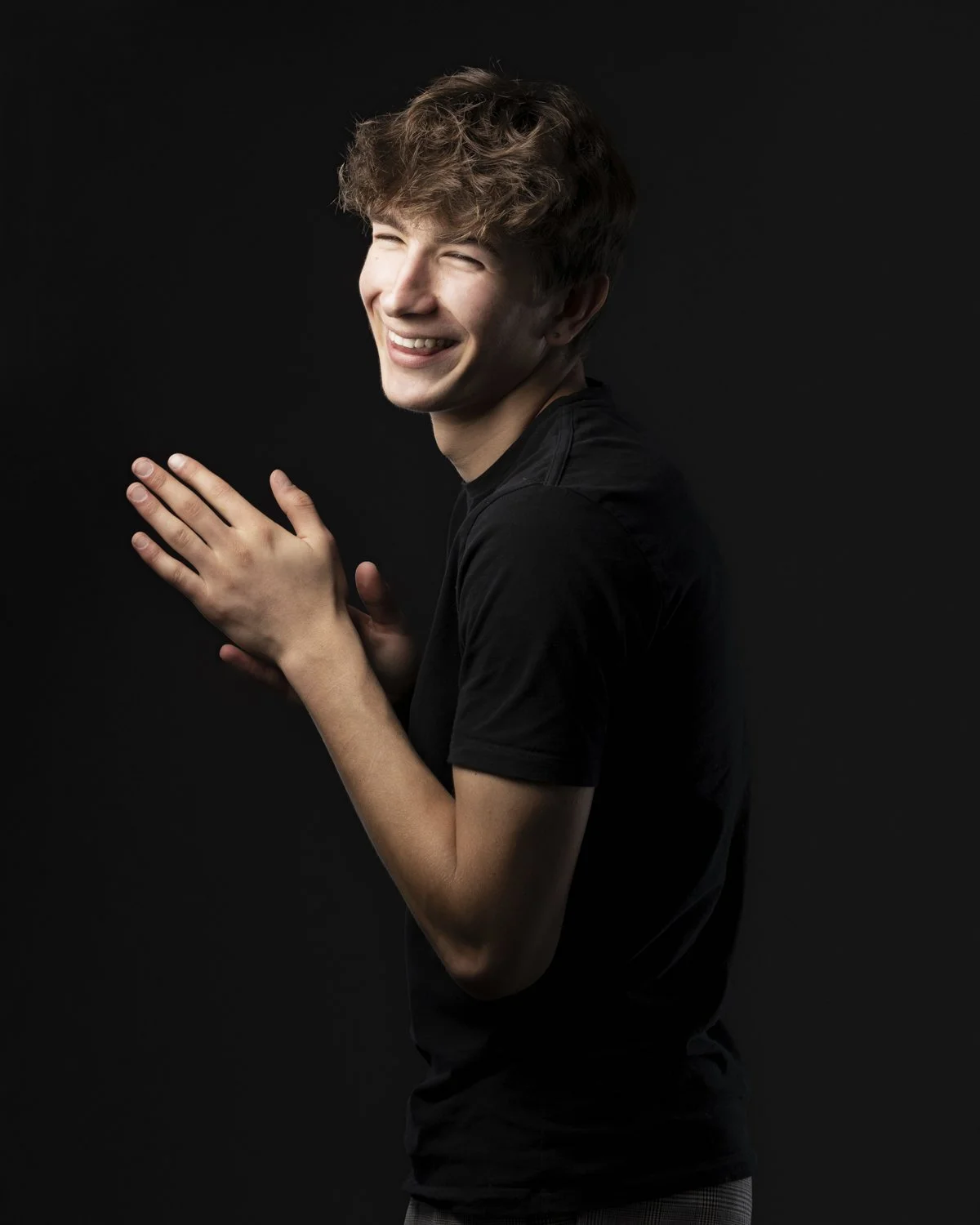 studio-boy-portrait-dark-background-natural-laughing