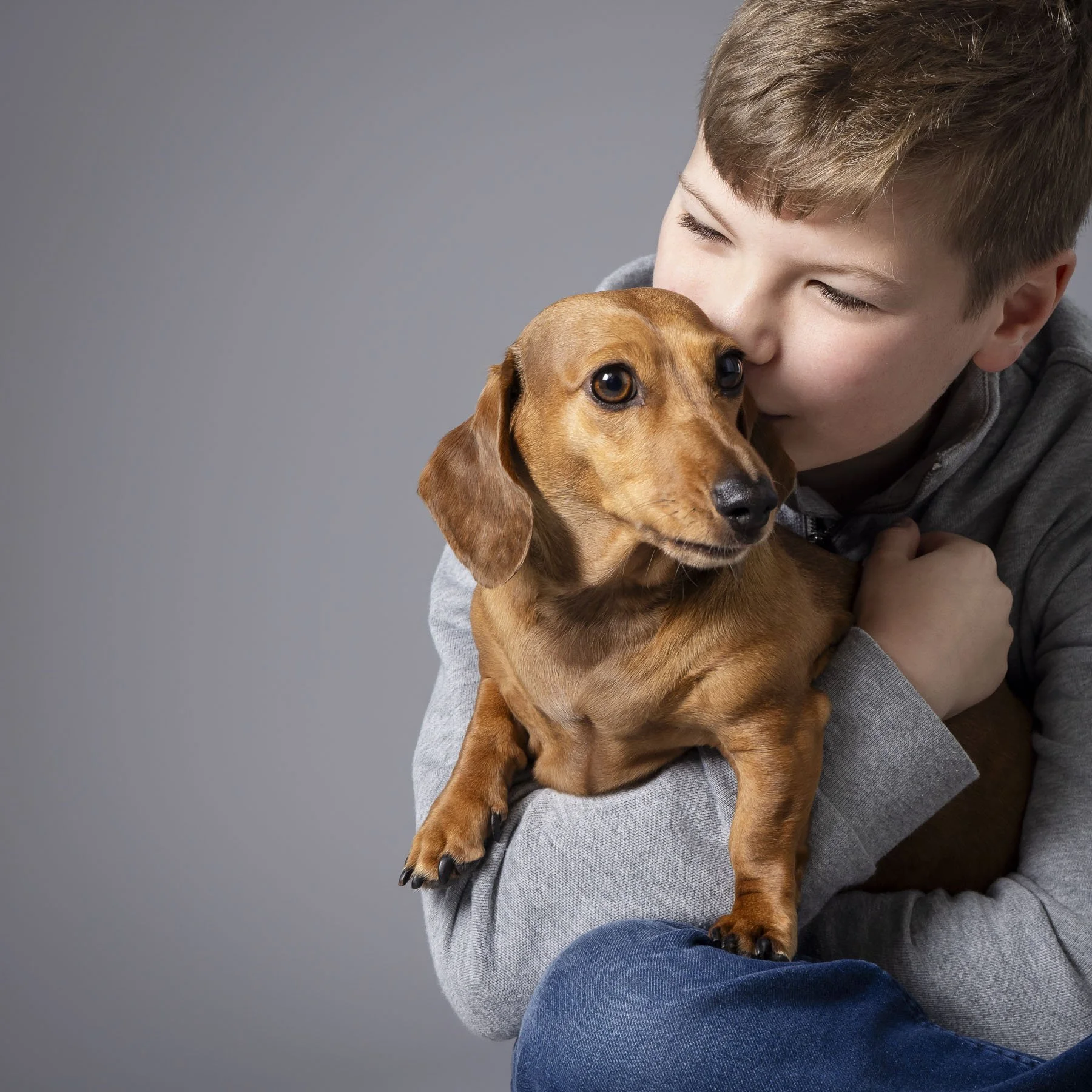 boy hugging his dog in a warm studio portrait, taken by Artis Studios in Berkshire