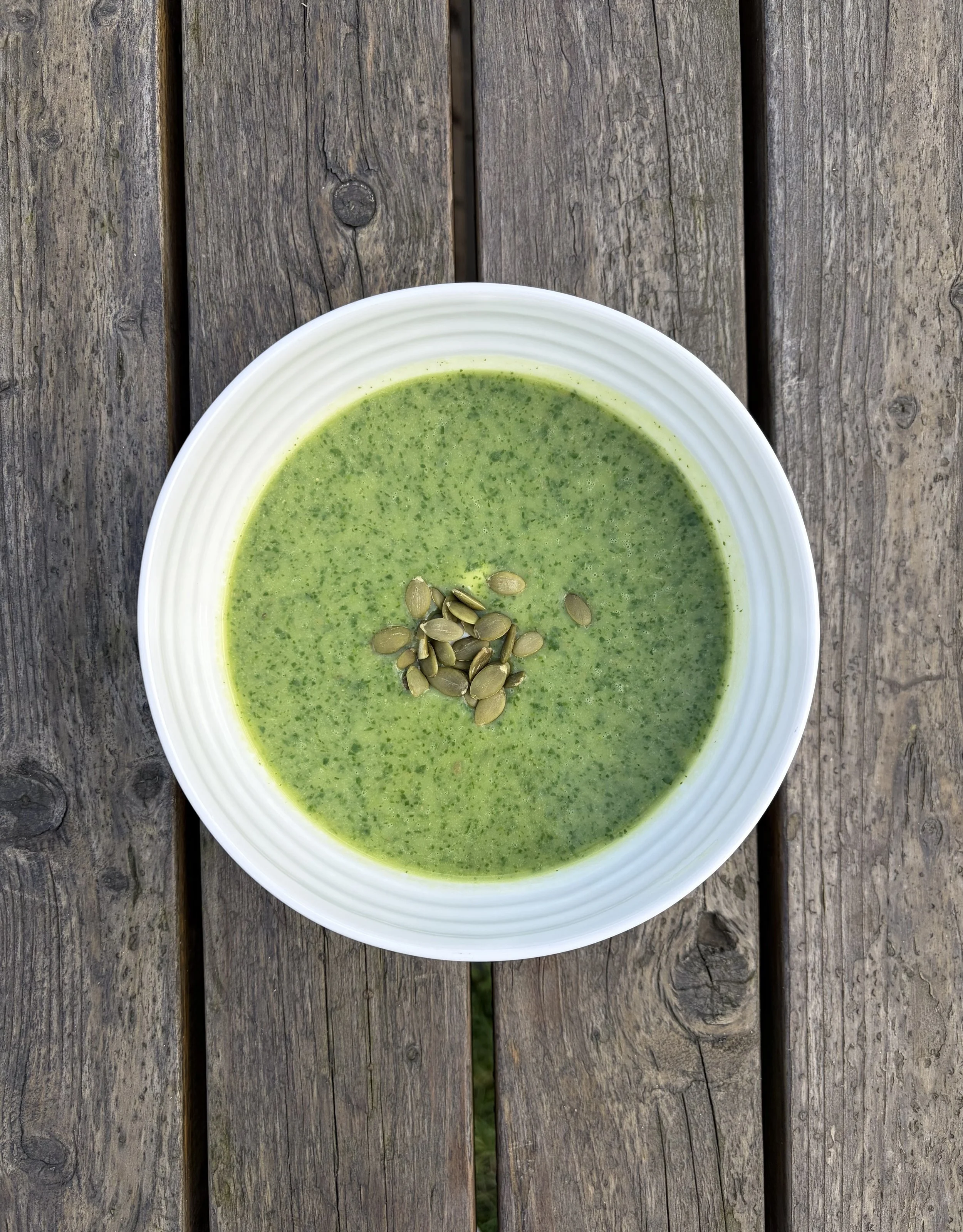 A bowl of green watercress soup on a wooden table top