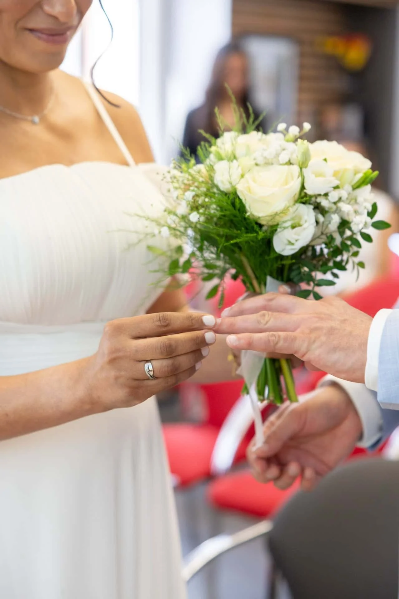 Femme en robe blanche recevant un bouquet de fleurs blanches lors d'une cérémonie de mariage