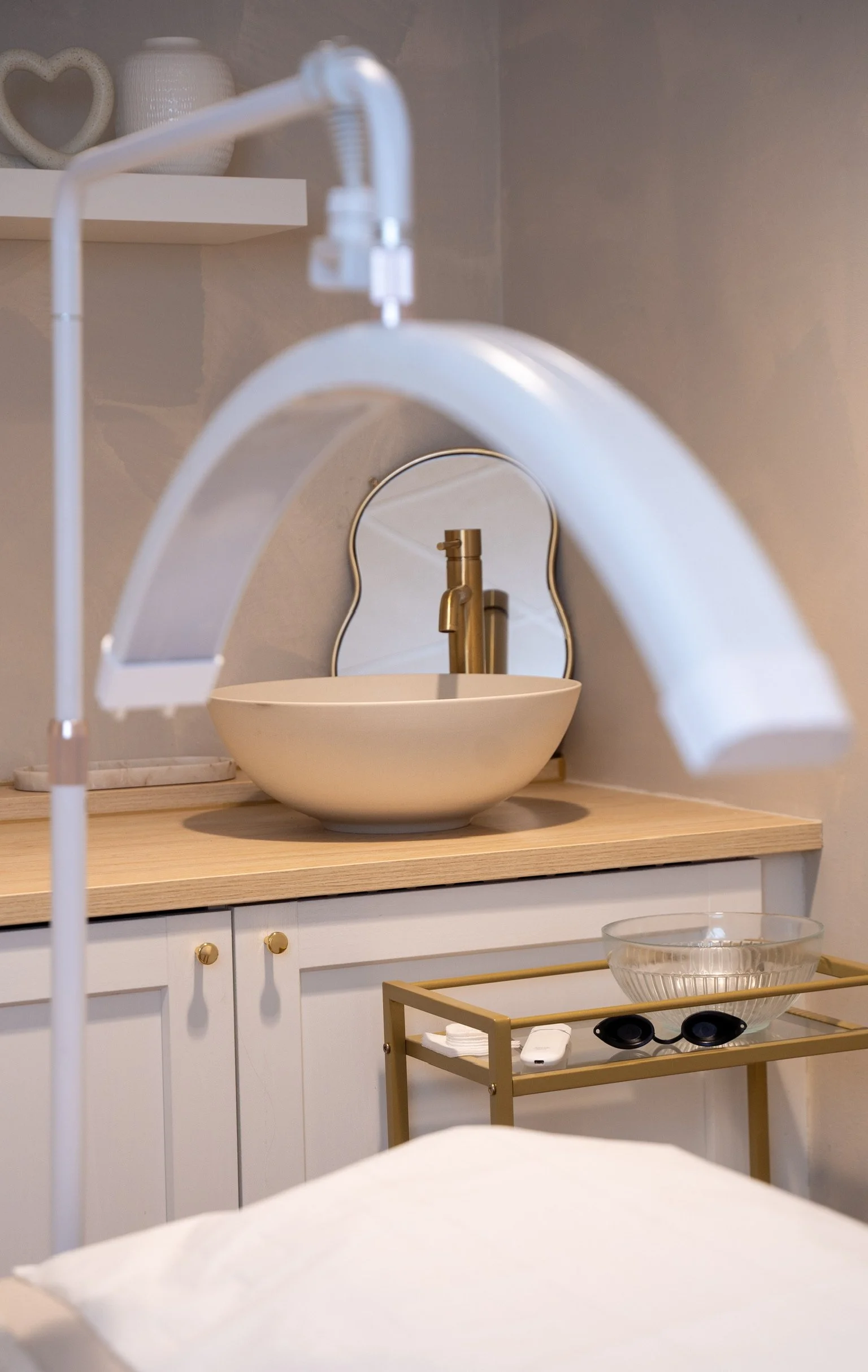 Modern spa room with bowl sink, decorative mirror, and medical lamp