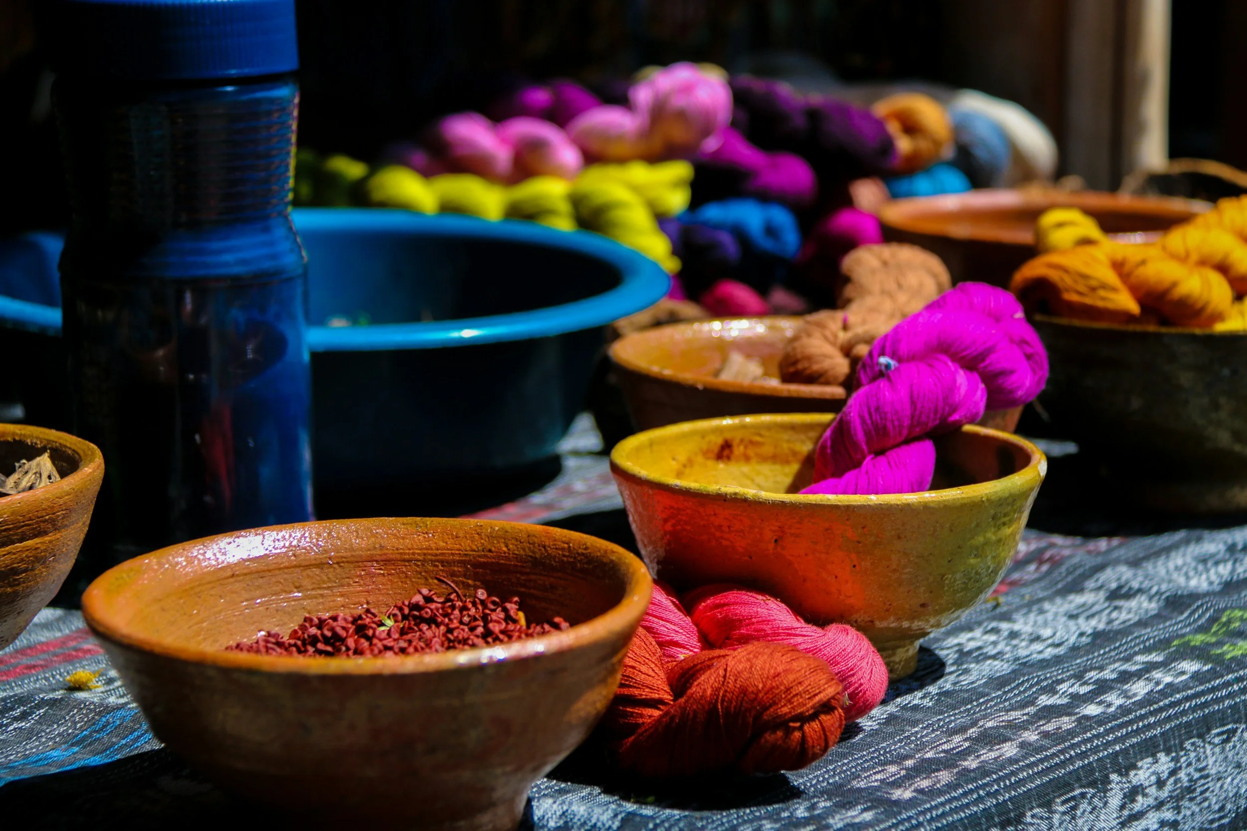 Colorful yarn skeins in bowls and containers on a table at a market stall.