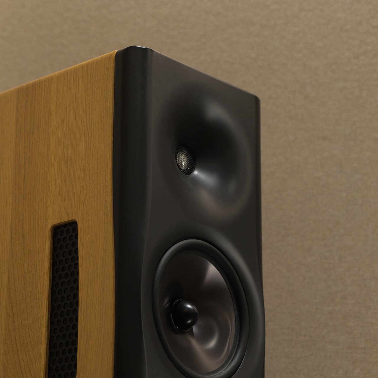 Close-up of a Dutch & Dutch 8c speaker with black front panel, including a tweeter and a woofer, against a beige wall.