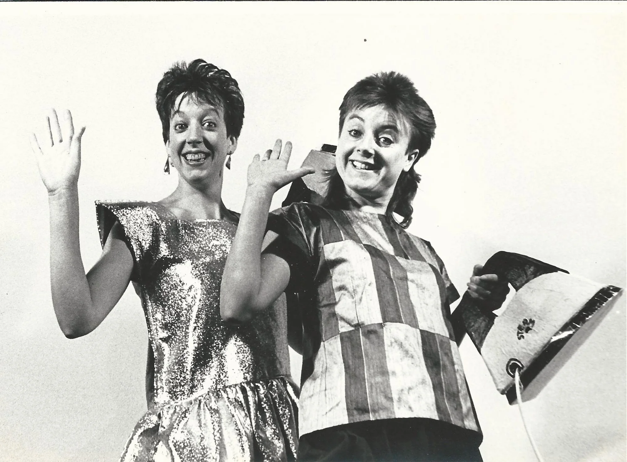 Maggie and Sue wave at the audience, clutching light up irons