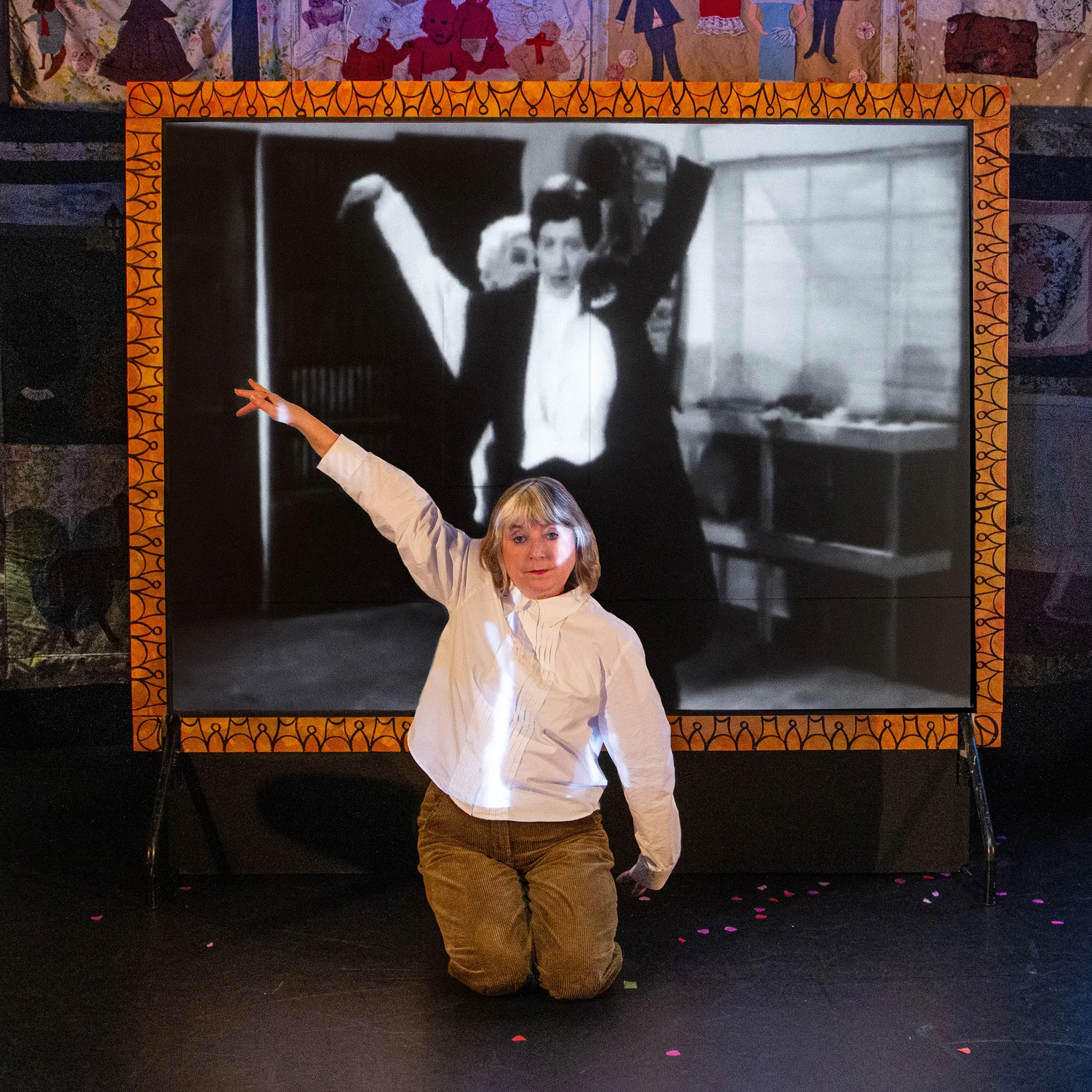 Sue dances an Egyptian style dance in front of a black and white film projection