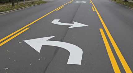 Two lanes on a road, one with a right turn arrow and the other with a U-turn arrow painted on the asphalt.