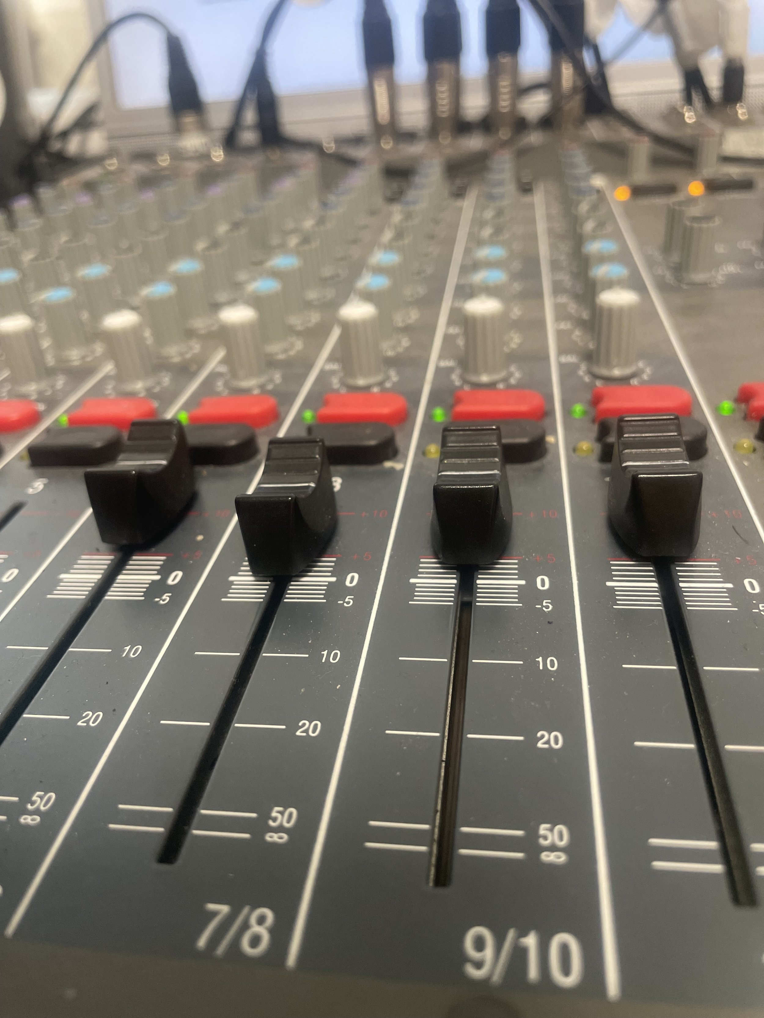 Close-up view of an audio mixing console with faders, knobs, and various controls.
