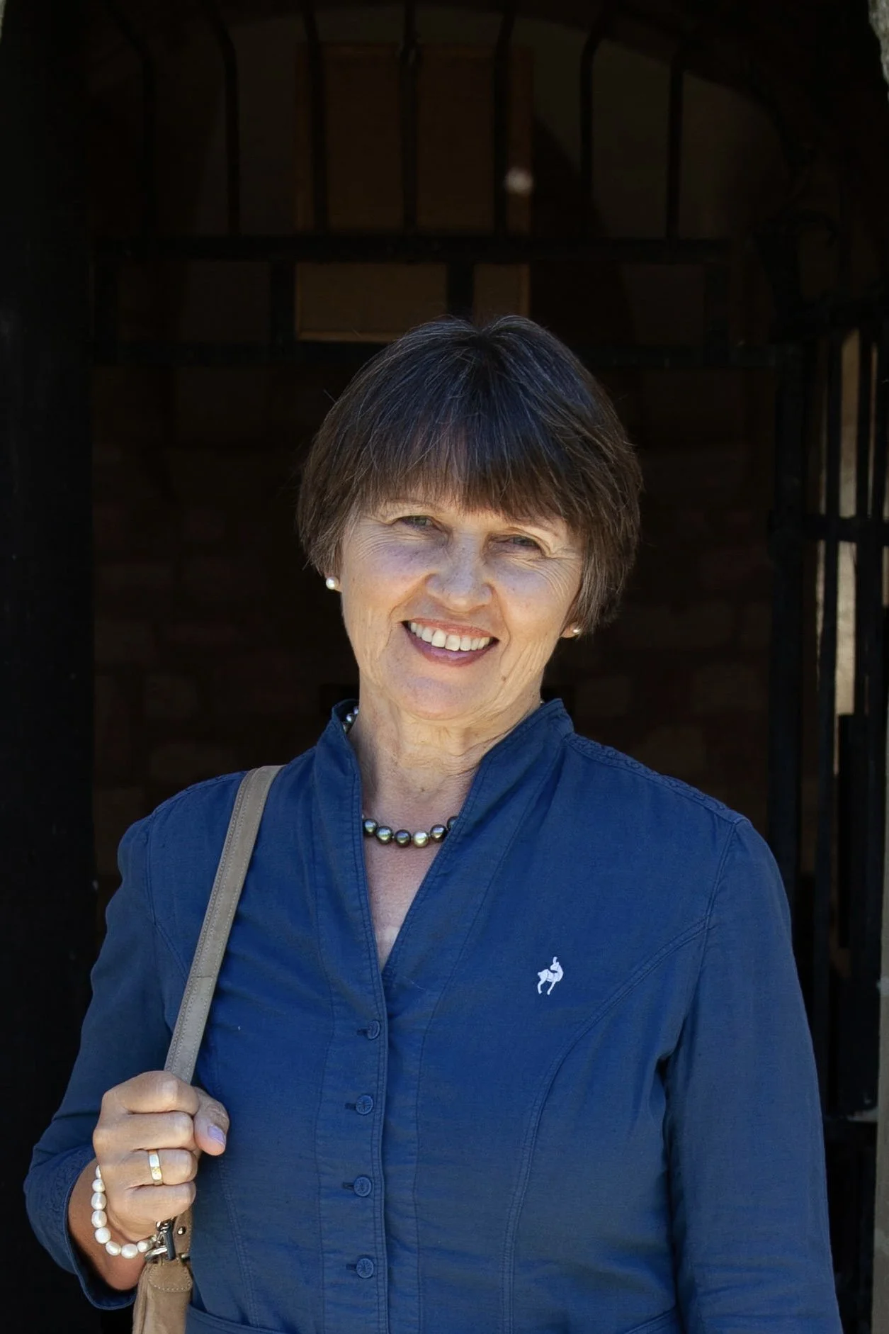 Frau in kariertem Hemd am Seeufer lächelt in die Kamera.